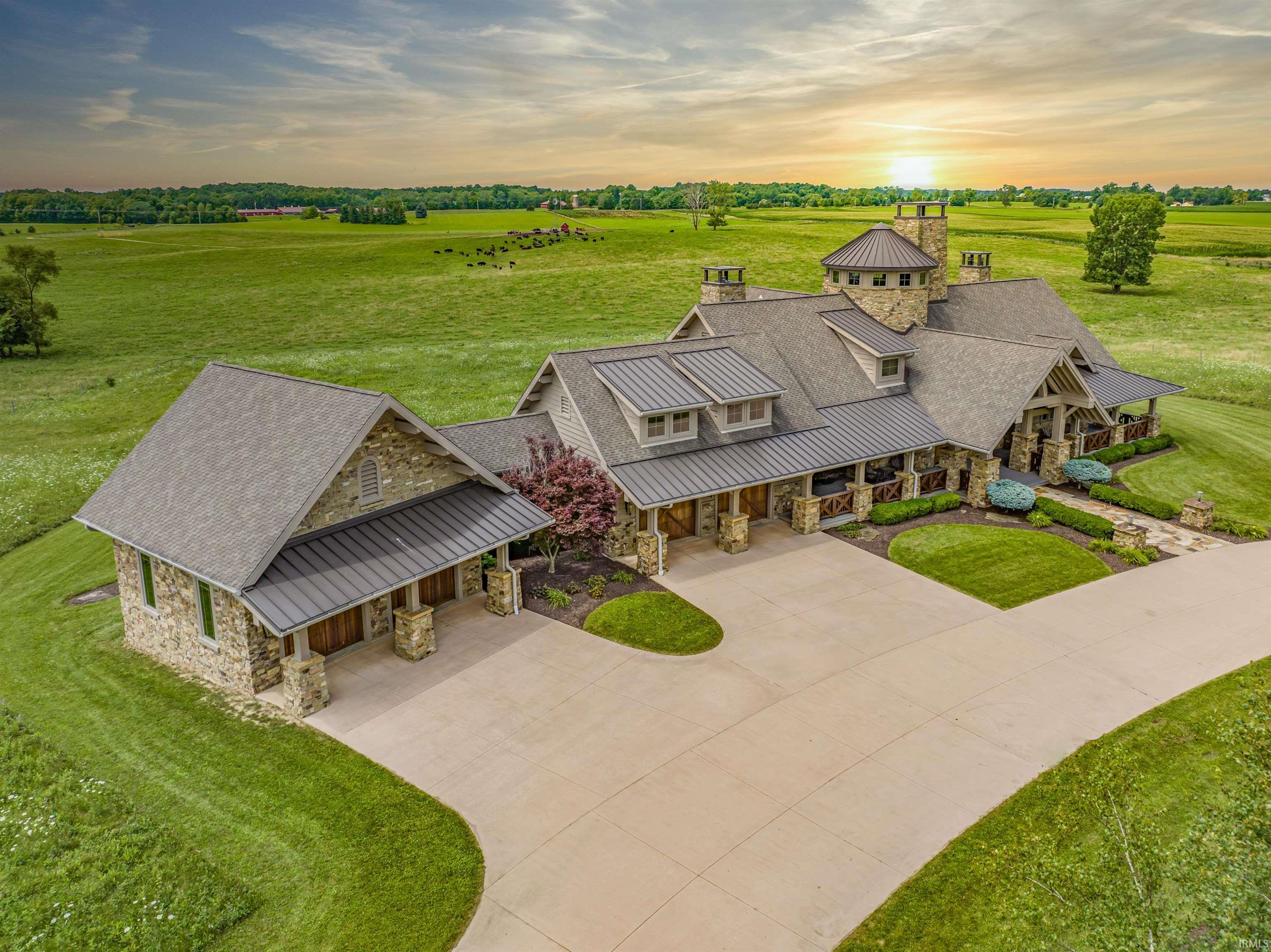 Welcome home to your own private paradise with a spectacular custom built 5,478 sq. ft. ranch on a walk-out lower level nestled on 13+ acres and overlooking nearly 100 additional acres of beautiful, lush pasture and wooded areas (facing west for sunsets!). Designed by a renowned Colorado architect and built by high-end builder Joe Hildenbrand, this masterpiece features ultra-luxe finishes, unparalleled quality, and thoughtful design features throughout, including natural stone, finely milled wood, granite finishes, 5 fireplaces, ultra-wide stairways, 13’ doorways, stunning wood trim, wood and vaulted ceilings with beams, and oversized windows and doors with sweeping views of the property.  The main floor features extra wide plank wood floors, a cupola 2-story dining room/foyer w/wood ceiling, a sunken family room w/vaulted ceiling and beams, an office/library w/coffered ceiling and more fabulous wood detail, guest powder room, large mud room/laundry/prep room w/storage galore, a chef’s dream kitchen, and a gracious primary bedroom en-suite featuring stone fireplace, private balcony, 2 gracious closets, walk-in stone-tiled shower, custom double-vanity and heated floor. The gourmet kitchen boasts a stone-faced wood-burning pizza oven, Wolf oven (8-burner+) w/hood, Jenn-air fridge drawers cabinet-faced Sub-zero fridge w/freezer drawers, 2 dishwashers, warming drawers, gracious island w/2nd copper sink, and charming eat-in area that overlooks property. Downstairs, the quality continues with 2 additional en-suite bedrooms (w/stone fireplaces, heated bath floors and private patios!), fitness area/sauna/full bath (with stackable washer dryer and steam shower!), elegant Tuscan-inspired wine room, and french doors leading to a stone patio. Sip a latte or glass of Vino on the maintenance free, Trex balconies or on the vast wrap-around porch. Extra bonus features include the 4-car heated garage w/storage walk-through, Tesla charger and generator. This is truly a meticulously crafted, prized property!