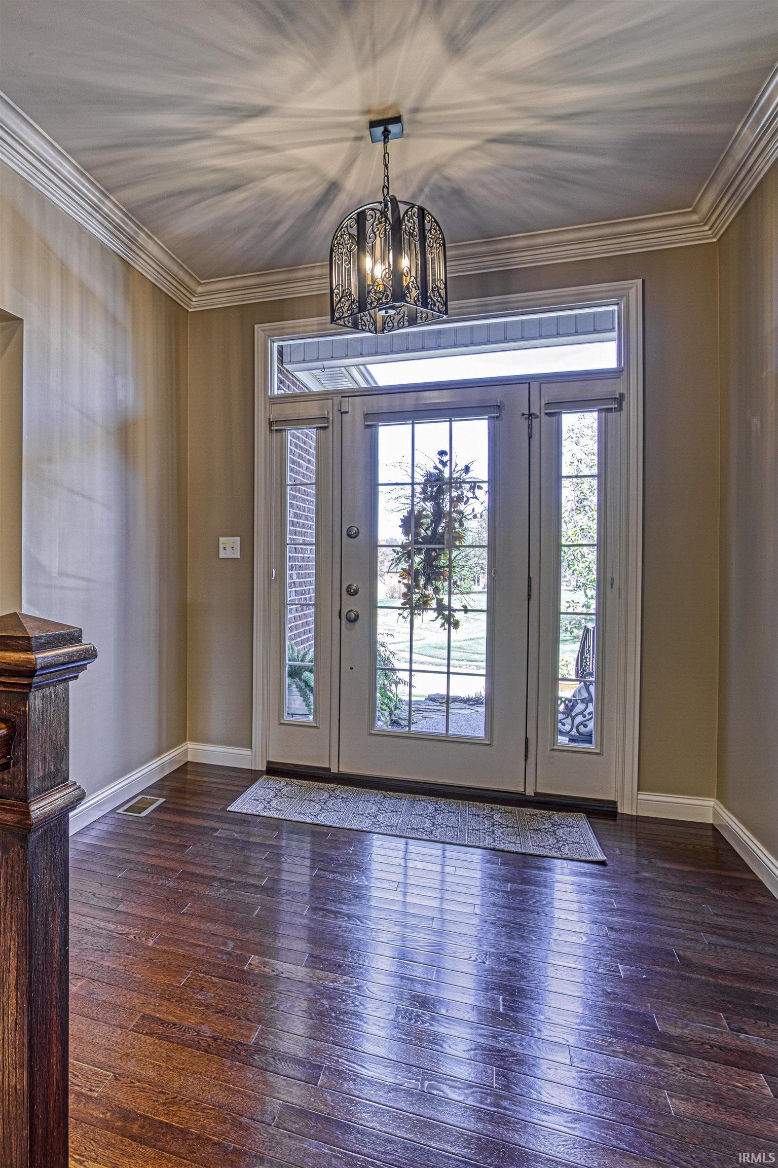 The foyer with gorgeous hardwood flooring and crown molding