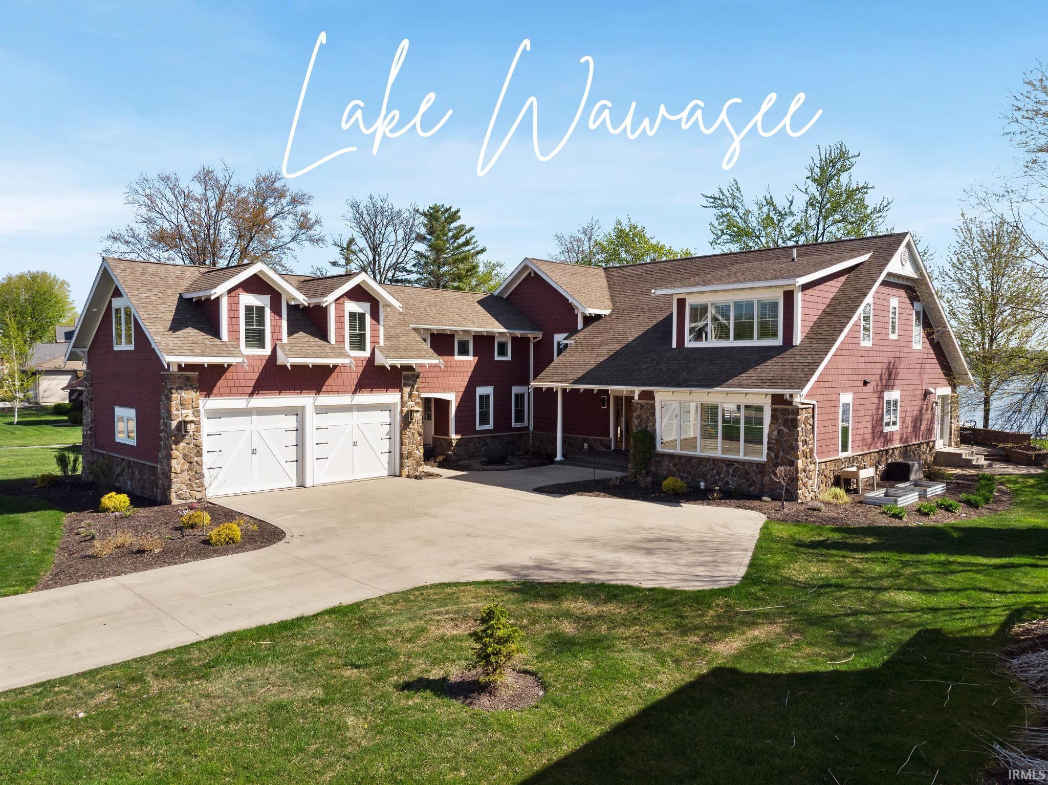 Gorgeous custom built home on Lake Wawasee w/plenty of room for family & friends (sleeps 24!) plus stunning 100’ lake & channel front for total of 200’ comes w/guest house & 2 car detached garage & boat house w/3 covered boat slips—ultimate lake retreat or year round home! Nestled on .58 acres in prestigious, private Bayshore Beach on zero through traffic road, this 7 bedroom, 6.5 bath home has everything you need for entertaining or enjoying gorgeous lakefront views. Stately main house faces E so you can catch sunrise from multiple rooms w/ attached 2 car garage, large parking apron & classic exterior of stone & shale siding. Impressive covered front entry has double sidelights allowing plenty of natural light into foyer linking to breathtaking open concept main living space featuring exposed beam coffered ceiling, beautiful hardwood floors & warm earth tone color palette. Inviting living area complemented by floor-to-ceiling river rock fireplace, wall of windows & glass doors to covered lakefront porch in addition to full wet bar w/ wine fridge & built-in storage. Chef’s delight kitchen has massive island w/ seating, abundant cabinetry, granite counters, tile backsplash & top of line SS appliances. You’ll notice attention to detail, quality craftsmanship & high end materials utilized throughout. Formal dining off kitchen offers wrap around lake views w/2 sets of glass doors leading to outdoor living spaces. Luxurious main floor primary bedroom stars waterfront views, private porch entrance & ensuite bath w/double sink vanity, soaking tub & tiled walk-in shower. Carpeted rec room off kitchen, half bath, cozy office & laundry/mud room w/ built-in storage & utility sink complete main level. Upstairs is amazing array of 5 more bedrooms (4 w/ensuite baths & 1 shared) as well as 2nd laundry room for your convenience. Many bedrooms hold multiple beds together w/ big bunk room w/ built-in beds & ample storage at every turn—excellent for guests, parties or any kind of hosting. Kick back & relax by lake on covered or uncovered patios w/ built-in fireplace & spectacular views w/piers front & back. Guest house/cottage on channel provides additional 812 sq ft, is charming and entirely functional w/ full kitchen, spacious living/dining, 1 bedroom, bath & attached covered boat slip. Detached 2 car garage also channel side has 2 covered boat slips. This one of a kind home must be experienced—reach out today! Pier# 404 & 405. See linked virtual tour!