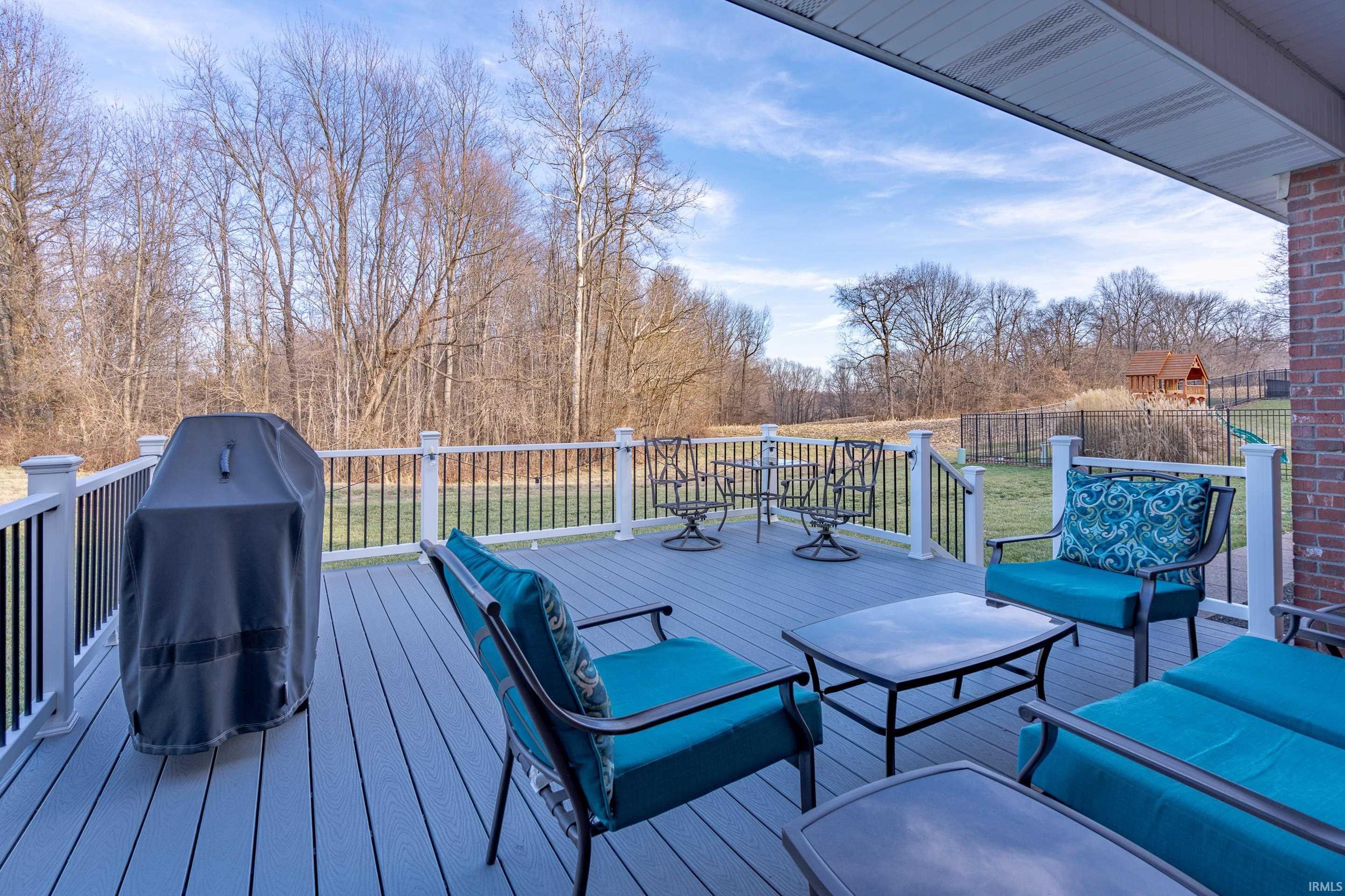 Deck overlooks private backyard with woods behind.