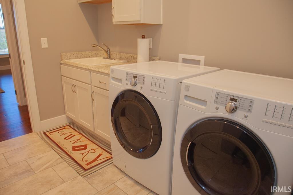 Laundry room offers a deep sink, cabinets & hanging area.