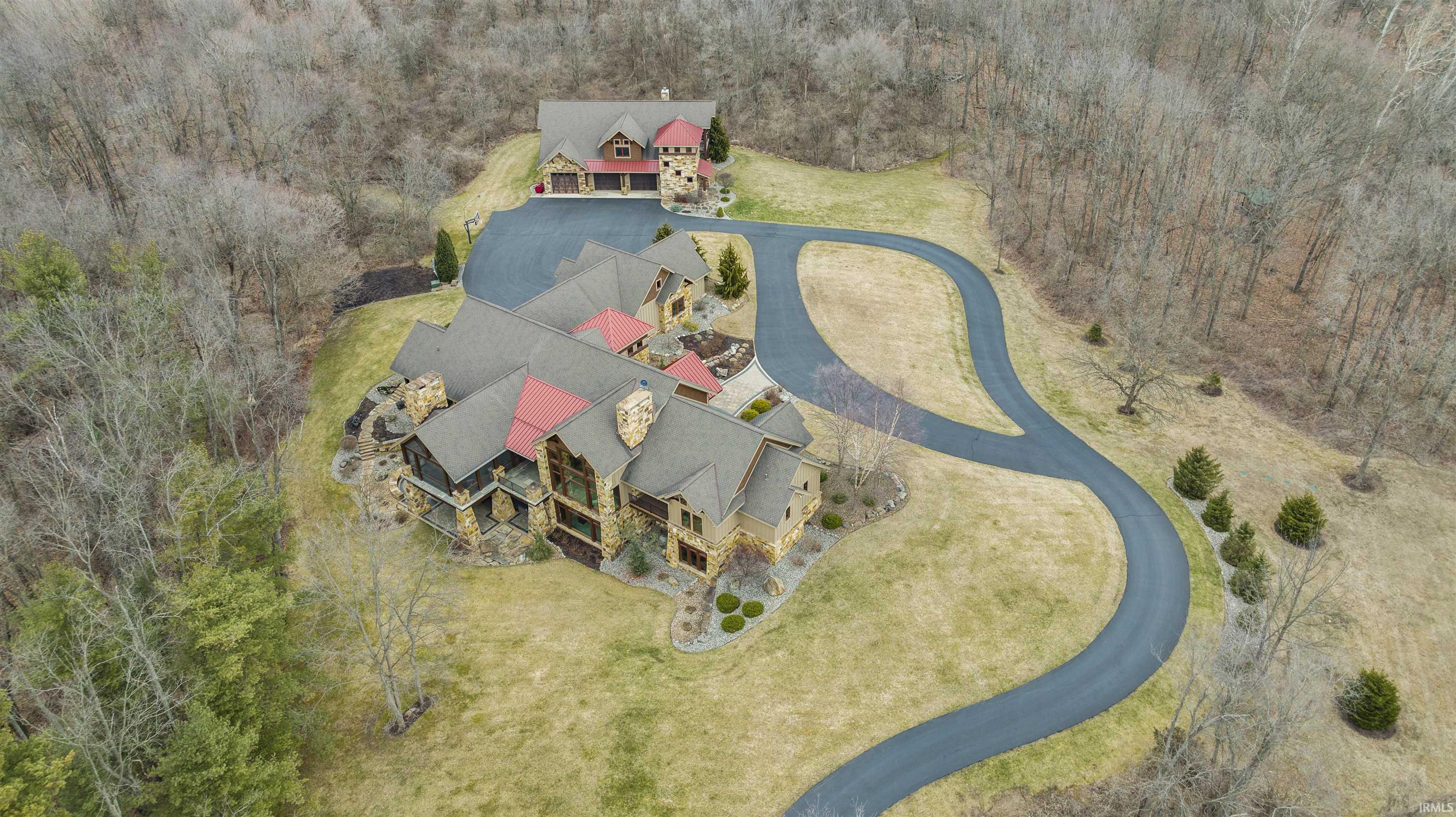 Just 1 mile from Ft. Wayne sits this one-of-a-kind private oasis w/12,000+ sq./ft. (2010) custom home and 3,000+ sq/foot Barn-dominium on 59+ partially wooded acres w/1/4-mile paved driveway and 1.3-acre stocked pond. Masterfully designed and crafted, the properties feature natural stone, Indiana-sourced wood for beams, stunning hardwoods, wood ceilings, slate tile, sweeping views, luxury finishes at every turn, pro landscape/hardscape (irrigated w/LED lighting), and state-of-the-art technology. The main home features open concept living w/2-story beamed timber-frame ceilings and floor-to-ceiling windows, 2-story stone fireplace + large dining area. The chef's kitchen boasts double granite islands, instant hot water, 6- burner/griddle Wolf cooktop + double Wolf wall ovens, Subzero oversized side-by-side, gracious walk-in pantry, 2 Asko dishwashers, & stunning custom built-ins. French doors lead to the timber-frame screened porch w/slate floors, 2-story stone fireplace, built-in stone grill, stunning views. The primary en-suite boasts a private balcony, oversized walk-in stone shower + copper accents, double vanity w/granite/stone, enormous walk-in closets & is cleverly connected to laundry room & mud-rooms. Off the foyer, a stone accented hallway leads to BRs 2 & 3, both large w/ stone/tile ensuites, walk-in closets and 12' ceilings, and the library (4th BR) w/private balcony, en-suite, and fabulous built-in shelves + desk. Don’t miss the 2nd story loft overlooking foyer and great rooms (more views!) w/ game/lounge area in the middle and doors on either end to walk-in floored attic (*future bedrooms). The finished walk-out lower level is an entertainers' paradise - 12-ft. ceilings, chef’s kitchen w/granite bar (seating for 6), open to living/game room w/stone fireplace. Sliders lead to fabulous covered outdoor space w/hot tub, 2-way stone fireplace, outdoor TV (*future pool). A large guest suite, tricked-out theatre room, fitness room, safe room (“Fort Knox”), and half bath complete the lower level. The detached Barn-dominium boasts 4 extra-long tandem bays (8+ car temperature-controlled), dog run, heated workshop (built-ins + epoxy floor), half bath, laundry room & mud room on the main level. Upstairs, 1700+ sq. ft., 2 BR/1 BA (dual shower + double vanity), luxury living area (slate, hardwoods, stone, granite) w/open concept, stone fireplace, and vaulted wood ceiling w/reclaimed wood beams. Security tied to main house + wired for sound.