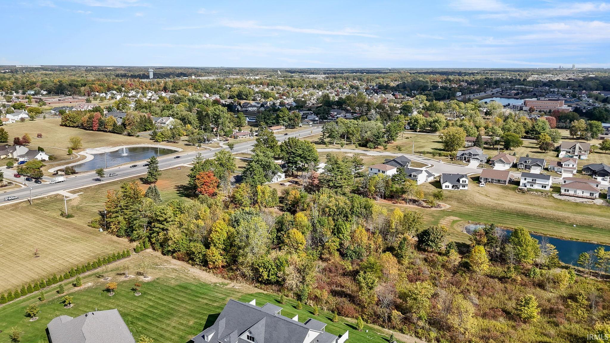 Aerial view of property and surrounding area featuring a nearby body of water and nearby suburban area