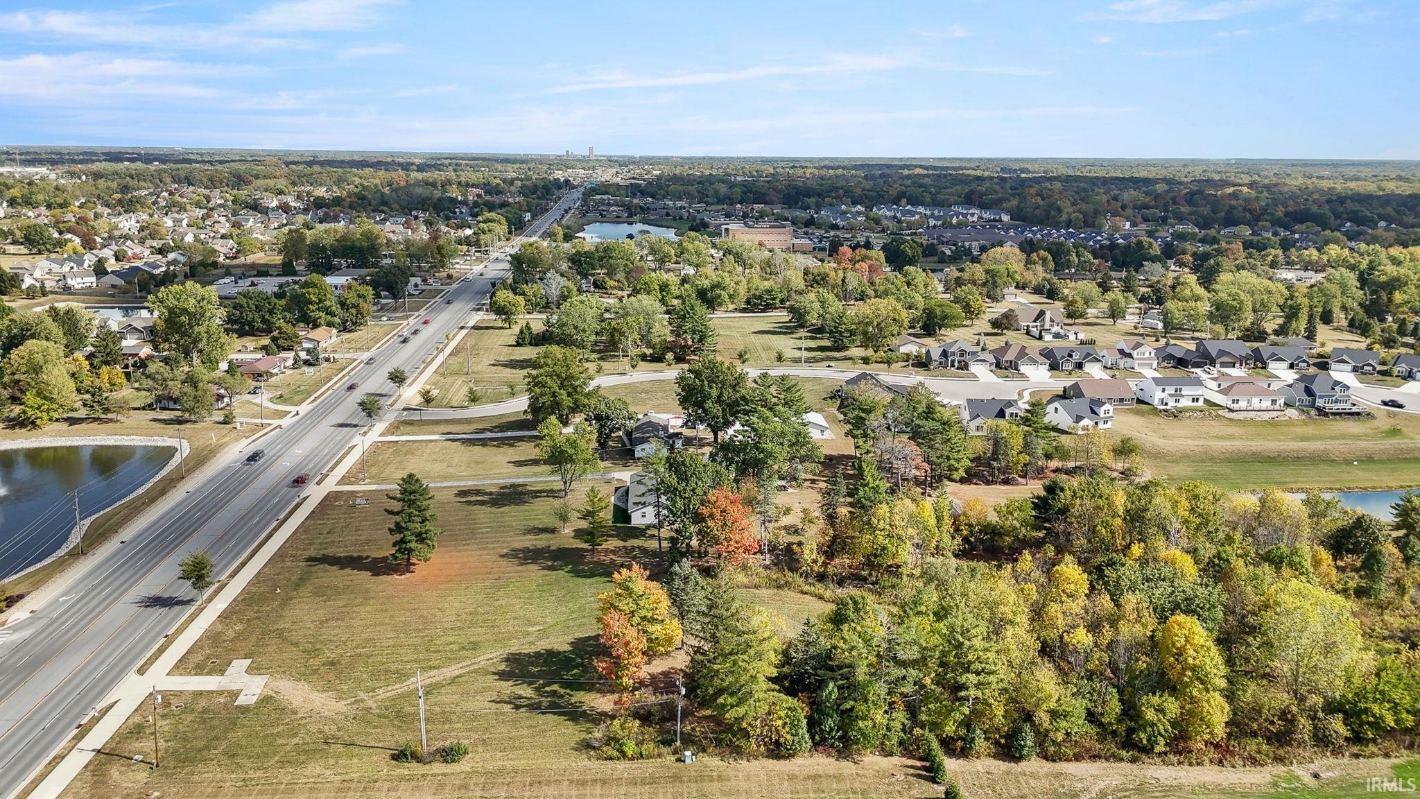 Aerial view of property and surrounding area featuring a nearby body of water and nearby suburban area