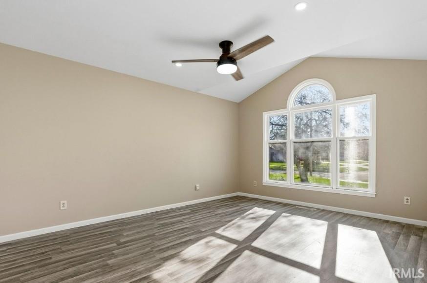 Empty room with vaulted ceiling, wood finished floors, and ceiling fan