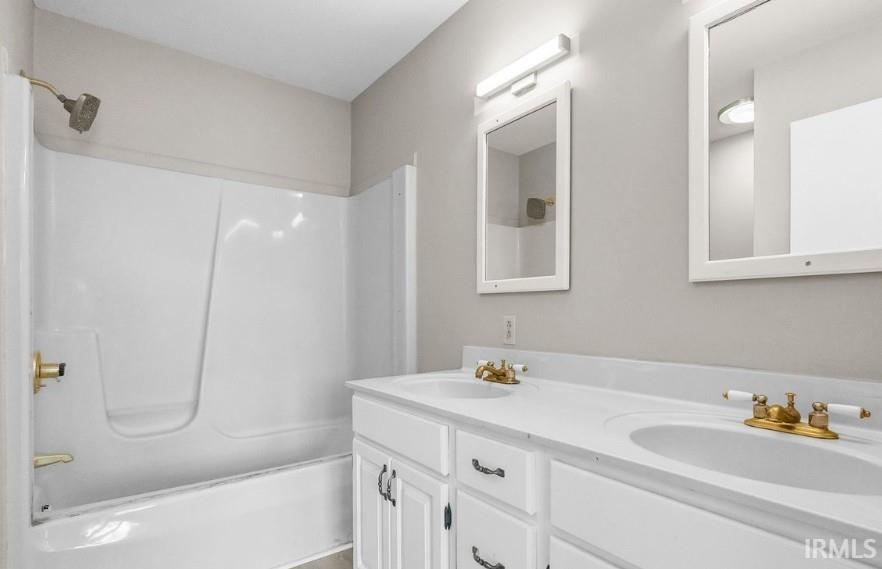 Bathroom featuring double vanity and bathing tub / shower combination