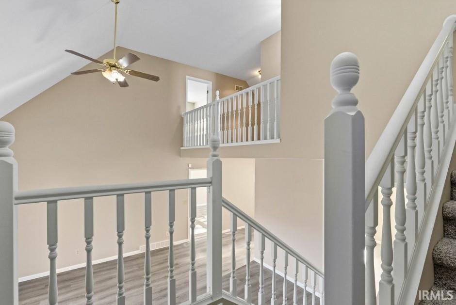 Staircase featuring high vaulted ceiling and wood finished floors