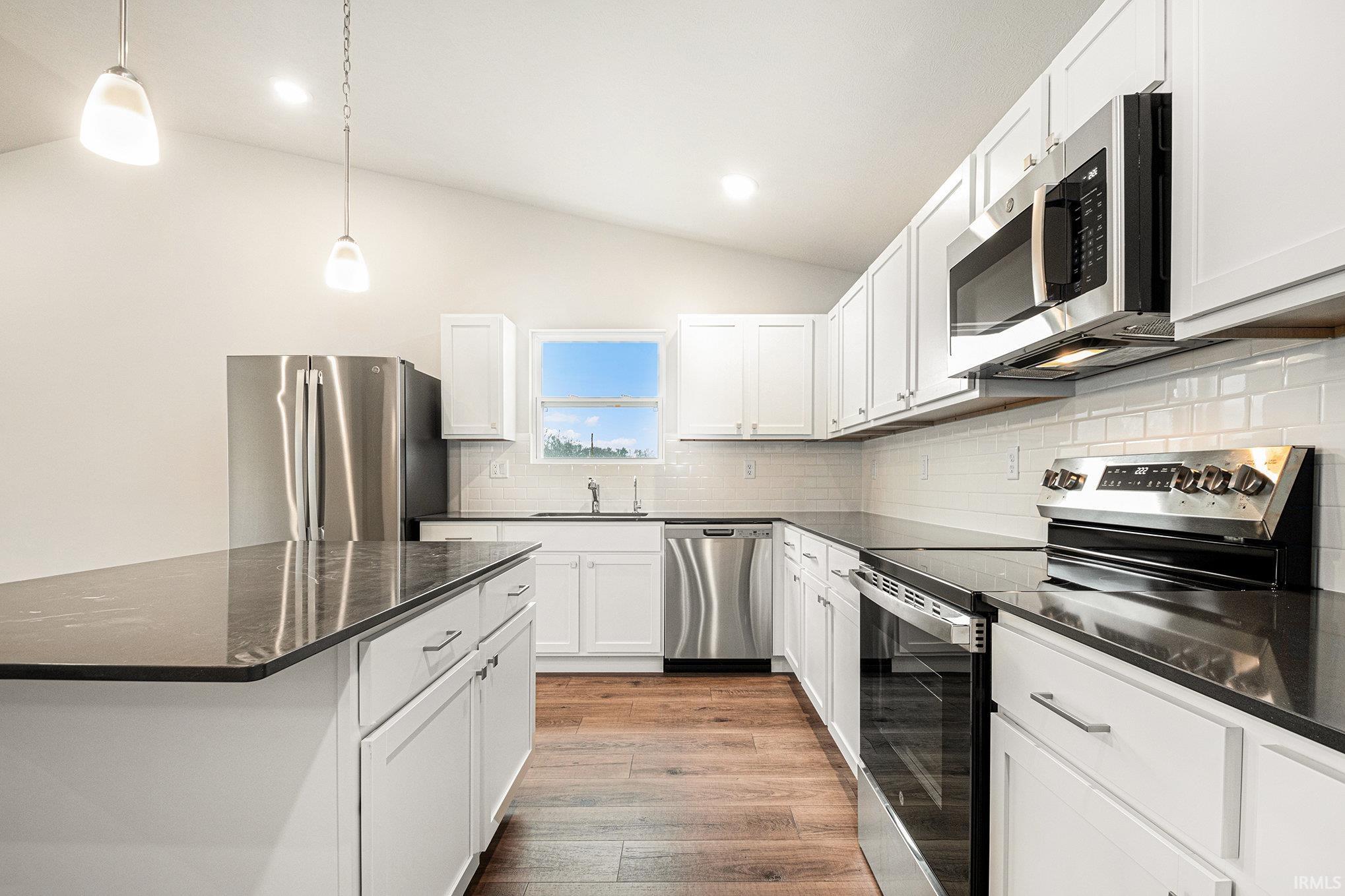 The kitchen includes Quartz counters with subway tile backsplash, large center island with extended edge counter and pendant lighting above.  Stainless steel appliances are included!