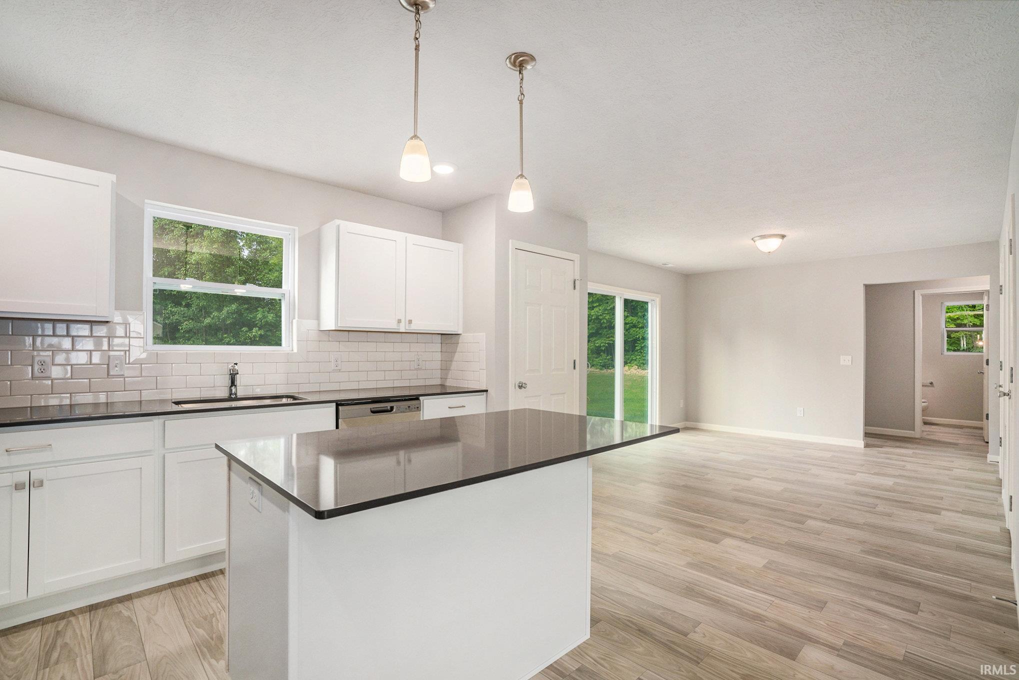 The kitchen includes a center island with extended seating and pendant lighting above.  Quartz counters are accented by subway tile backsplash. Stainless steel appliance package included.