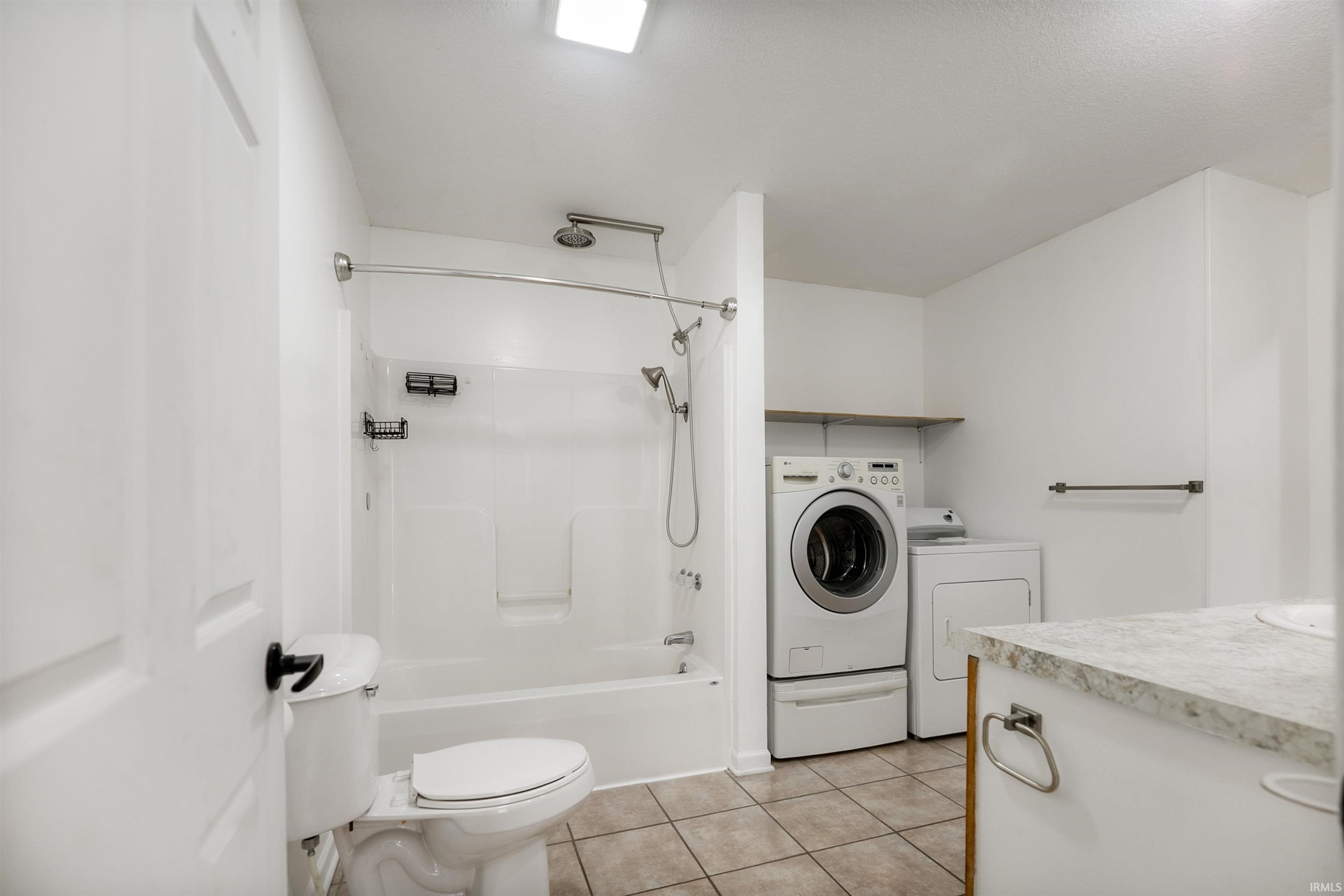 This bathroom has an entrance from the hallway and another from the primary bedroom. The laundry is located in this space as well.