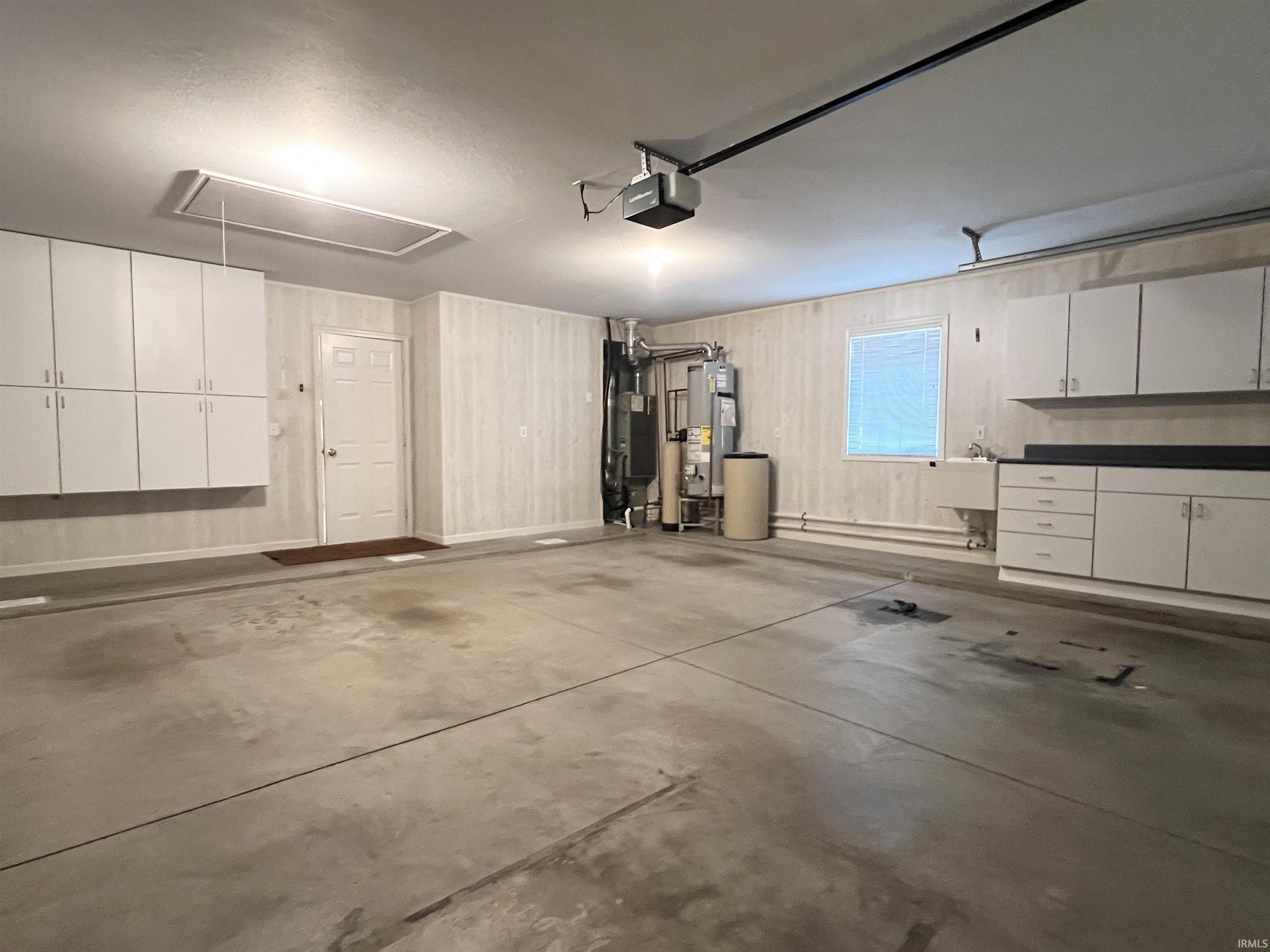 Garage with gas water heater, a garage door opener, and heating unit