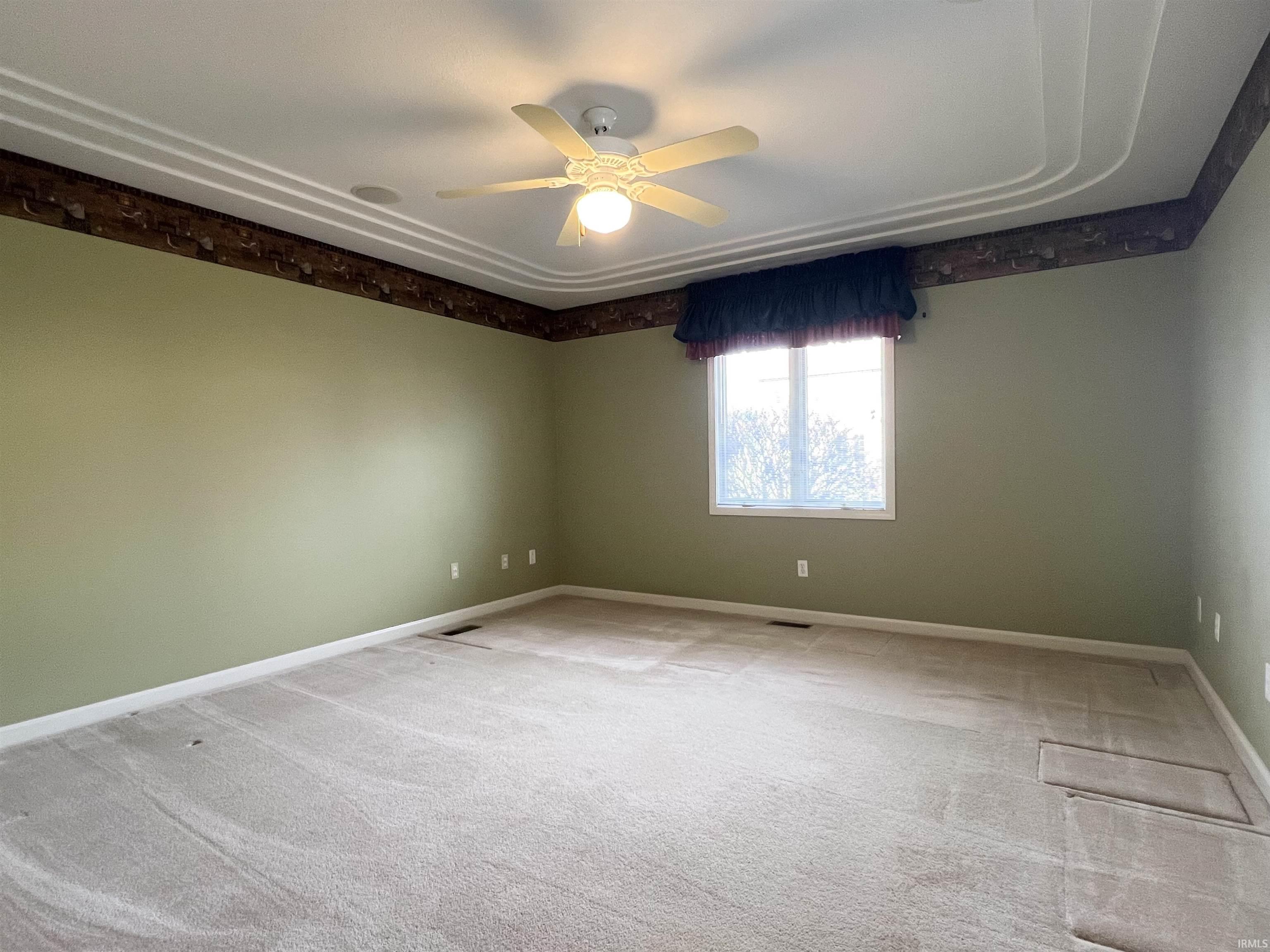 Carpeted empty room with a ceiling fan and baseboards