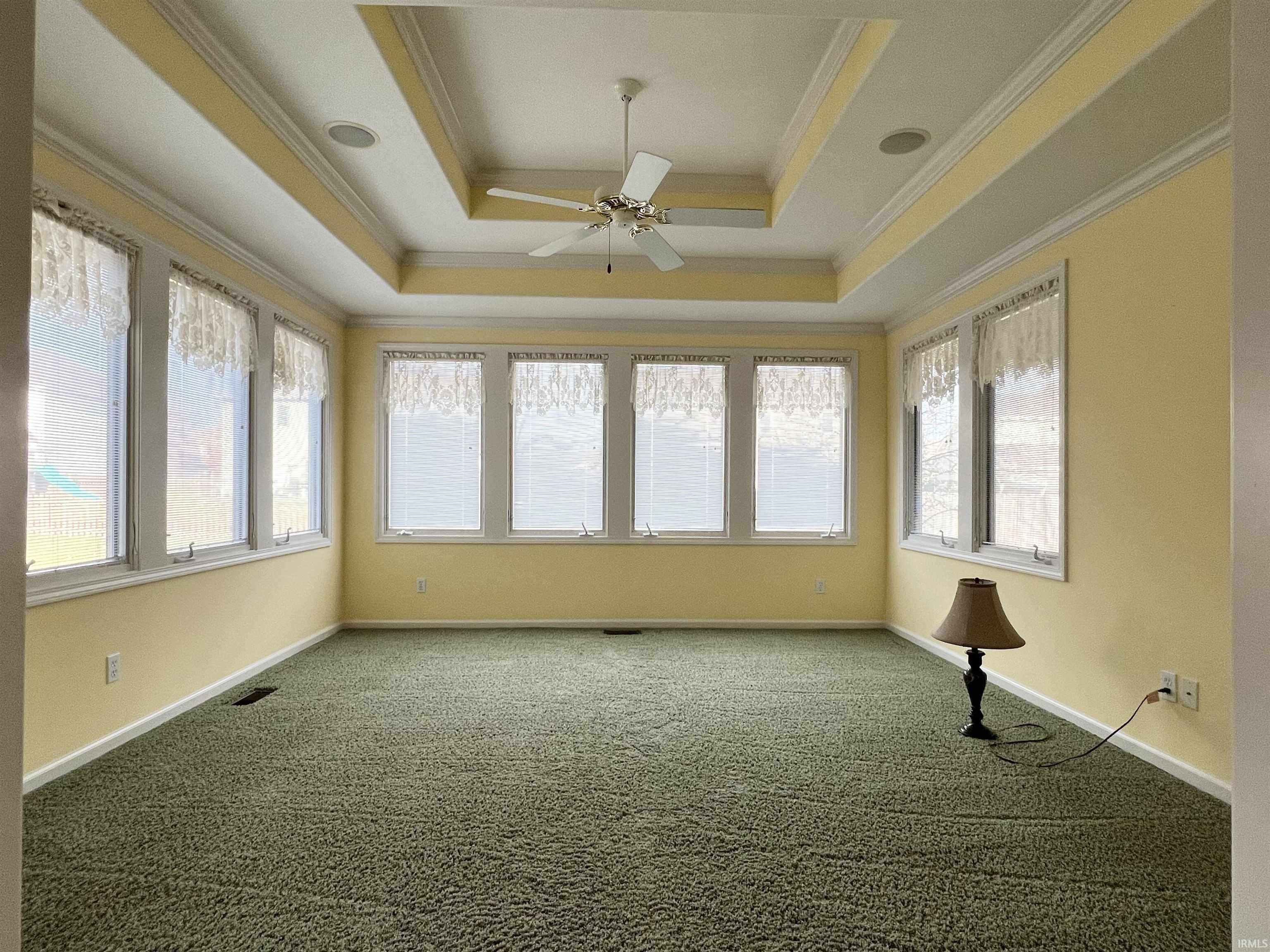 Unfurnished sunroom with ornamental molding, carpet floors, healthy amount of natural light, and a raised ceiling