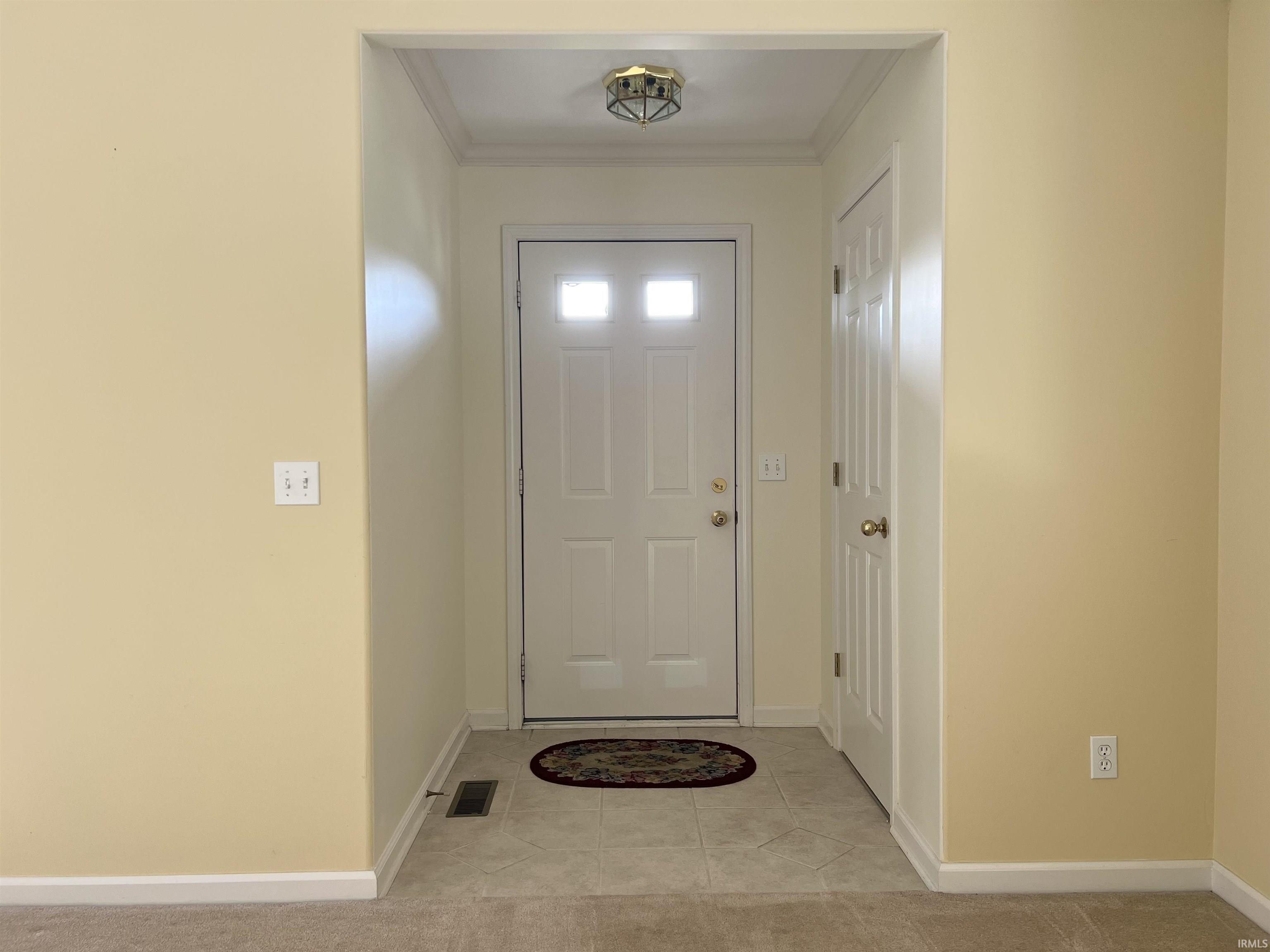 Entryway featuring tile patterned flooring and crown molding