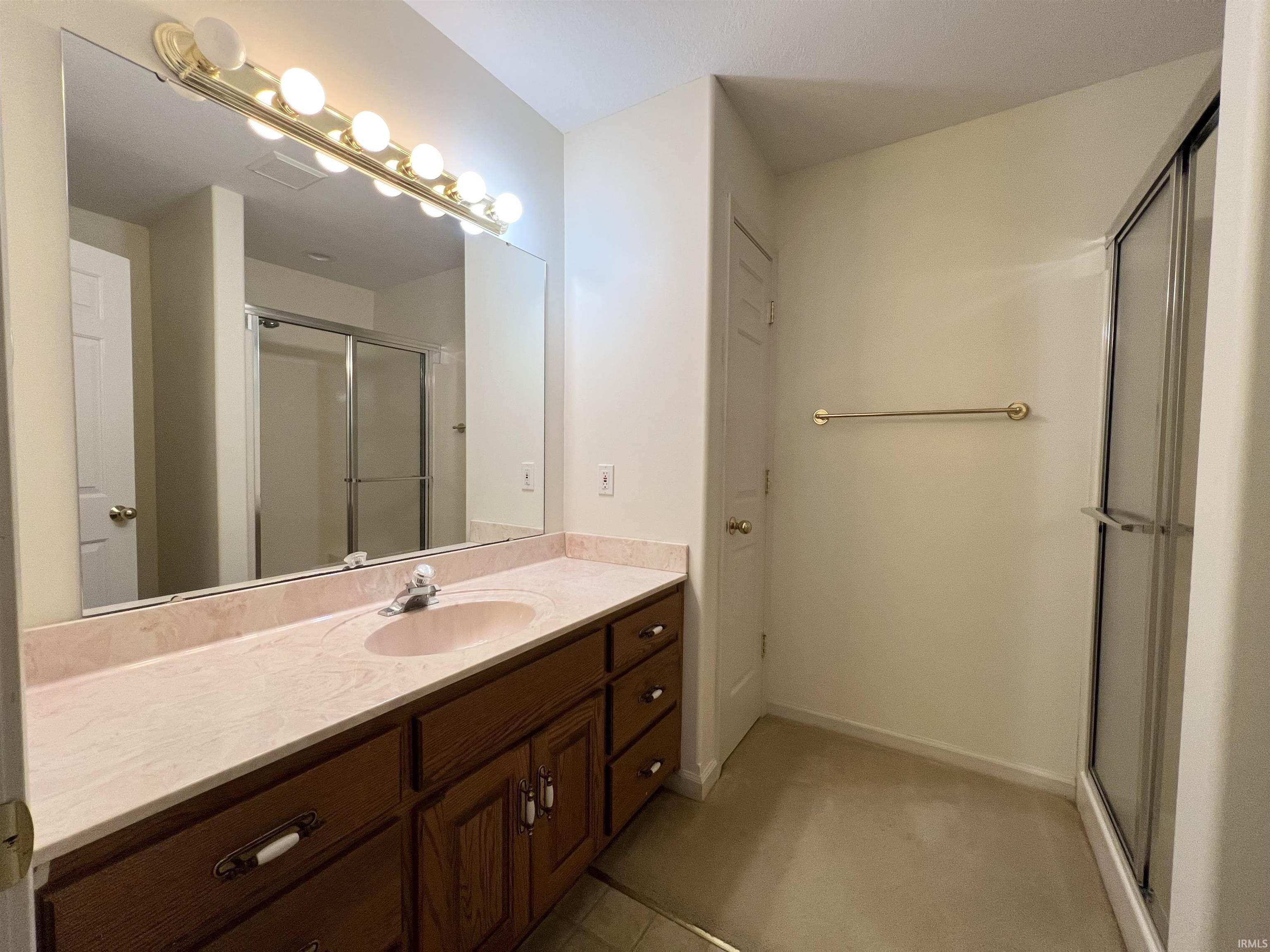 Bathroom featuring vanity, a stall shower, and light carpet
