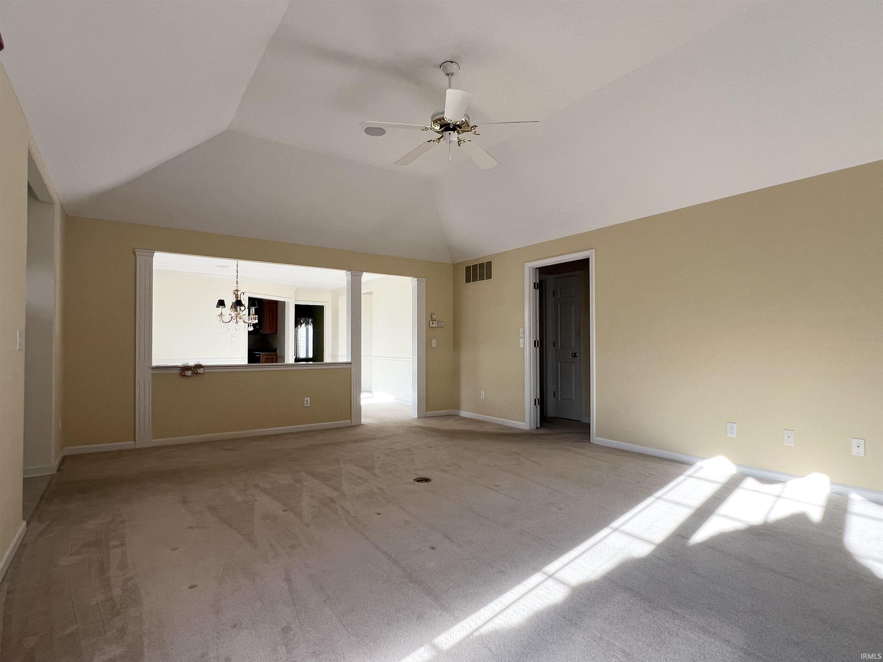 Unfurnished room featuring a chandelier, vaulted ceiling, and ceiling fan