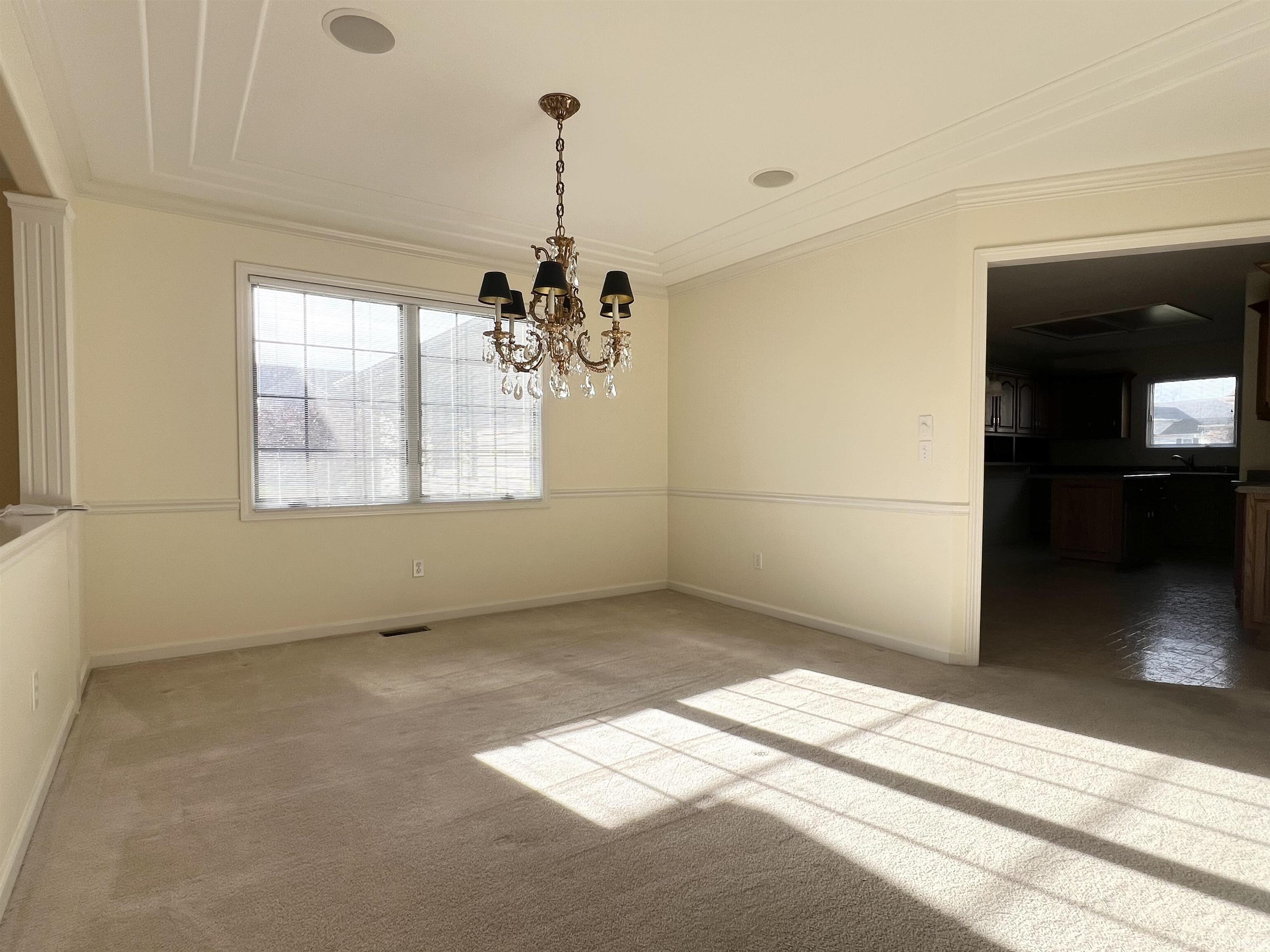 Unfurnished dining area with a chandelier, light carpet, and crown molding