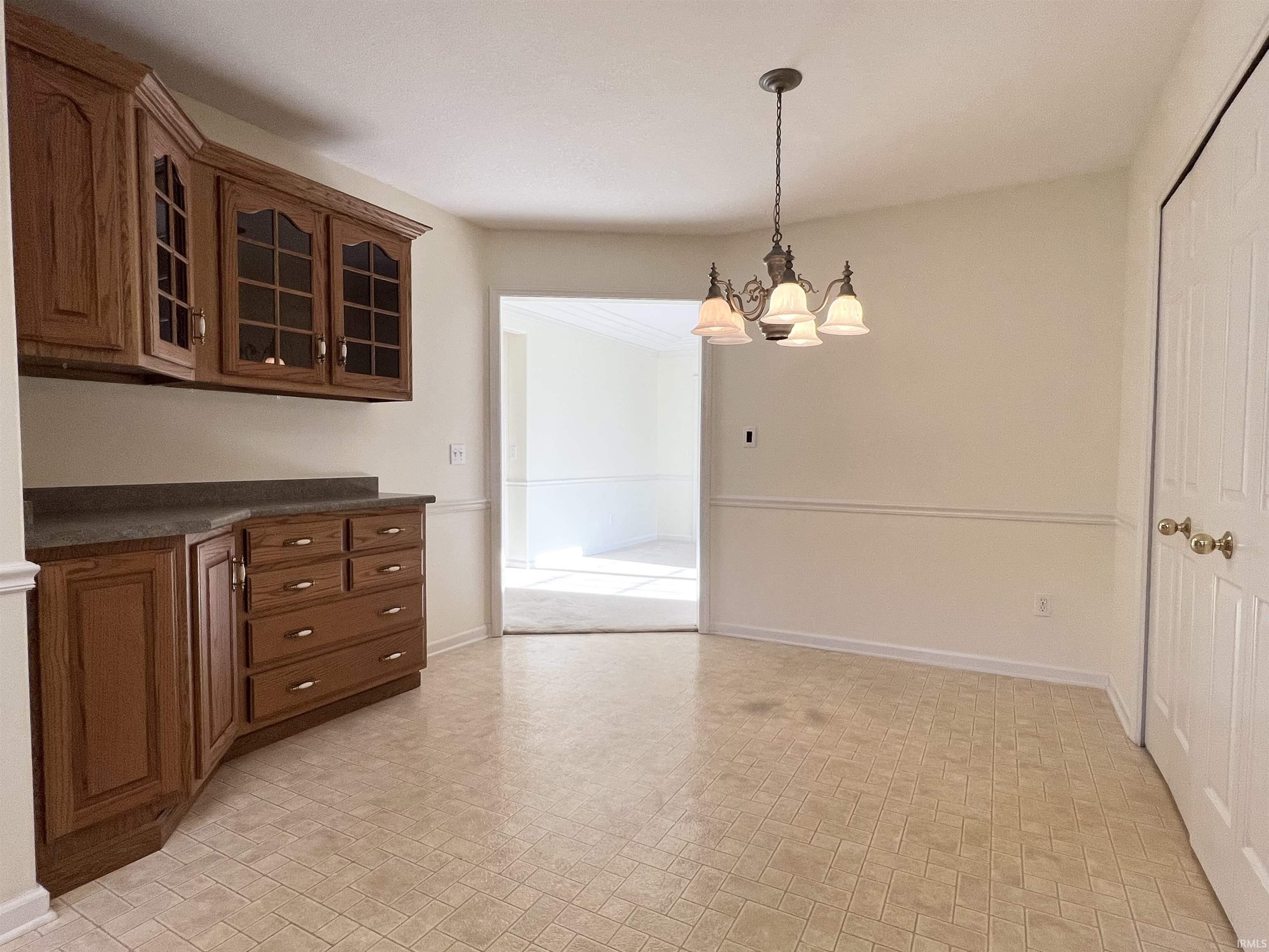Unfurnished dining area featuring brick patterned floors and a chandelier