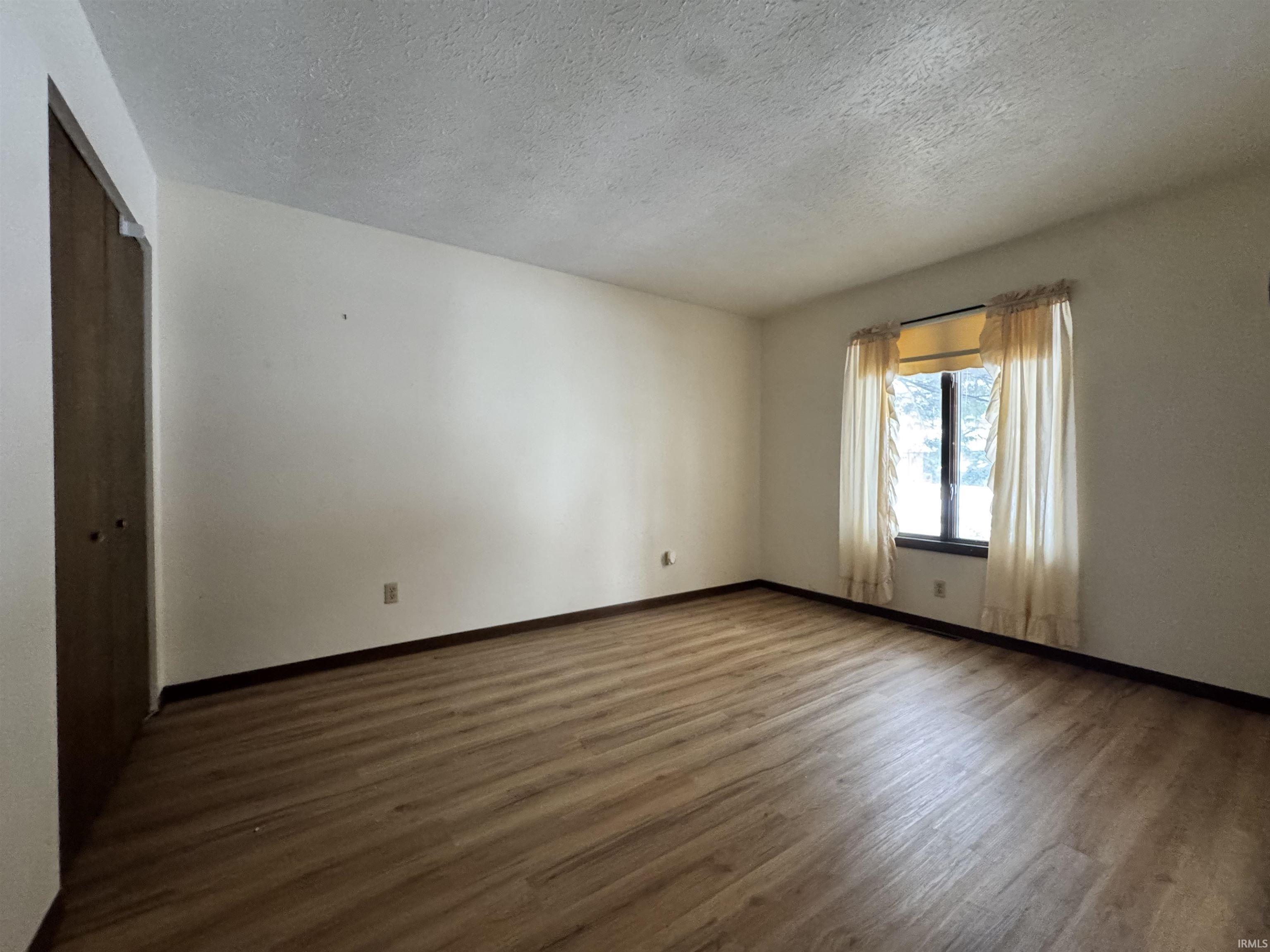 Spare room with dark wood-style floors and a textured ceiling