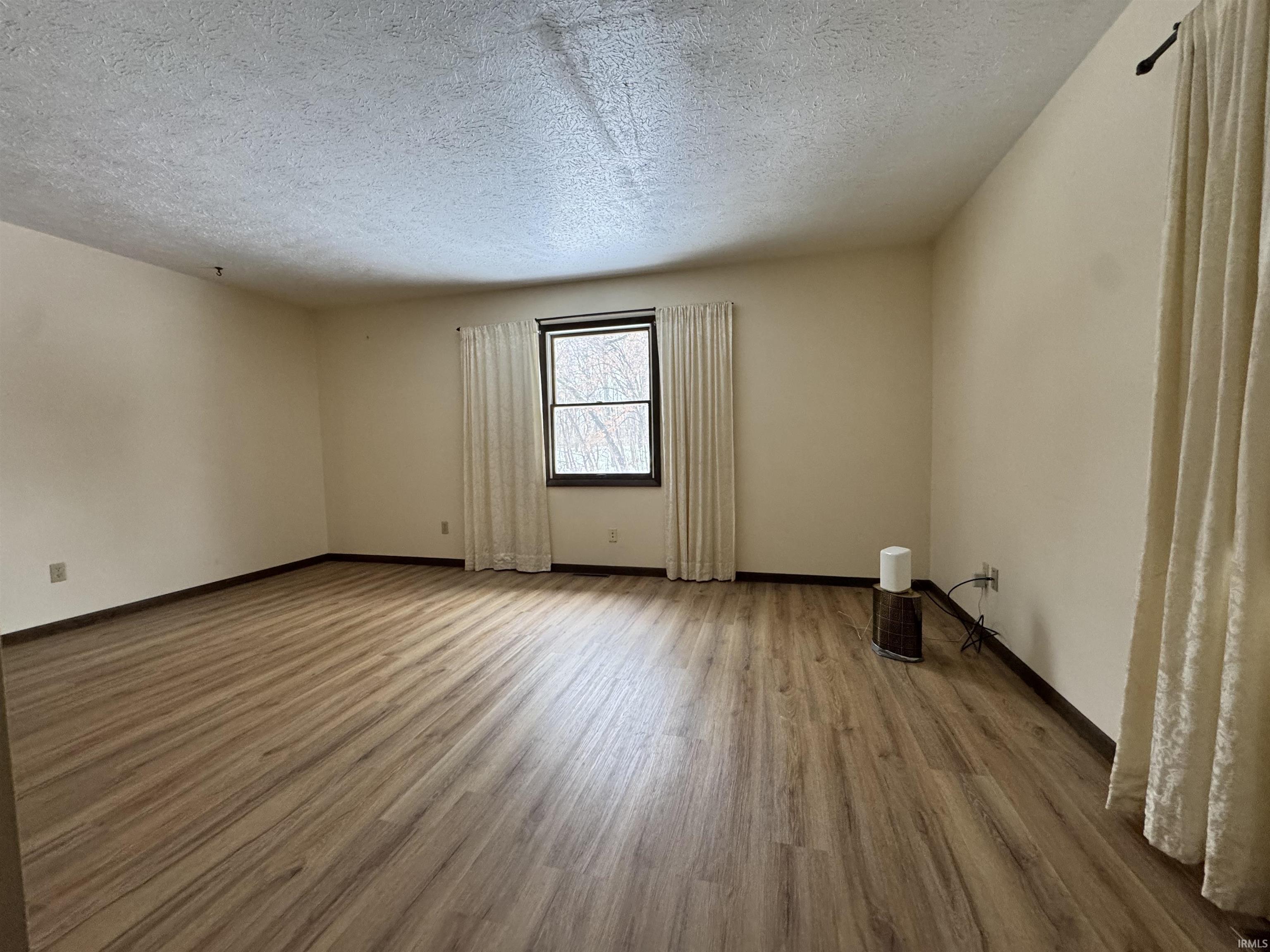 Empty room featuring wood finished floors and a textured ceiling