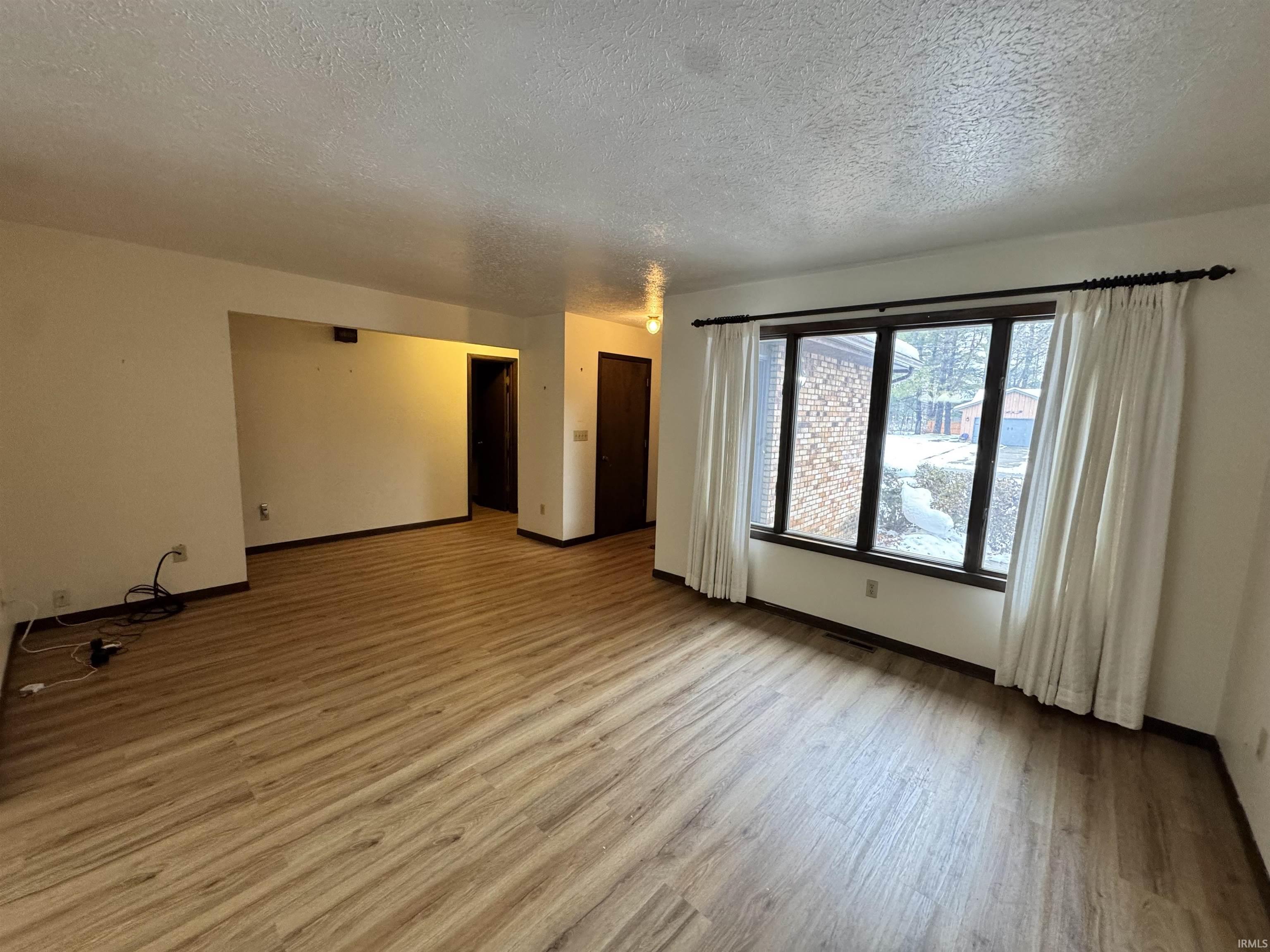Empty room with a textured ceiling and light wood-style flooring