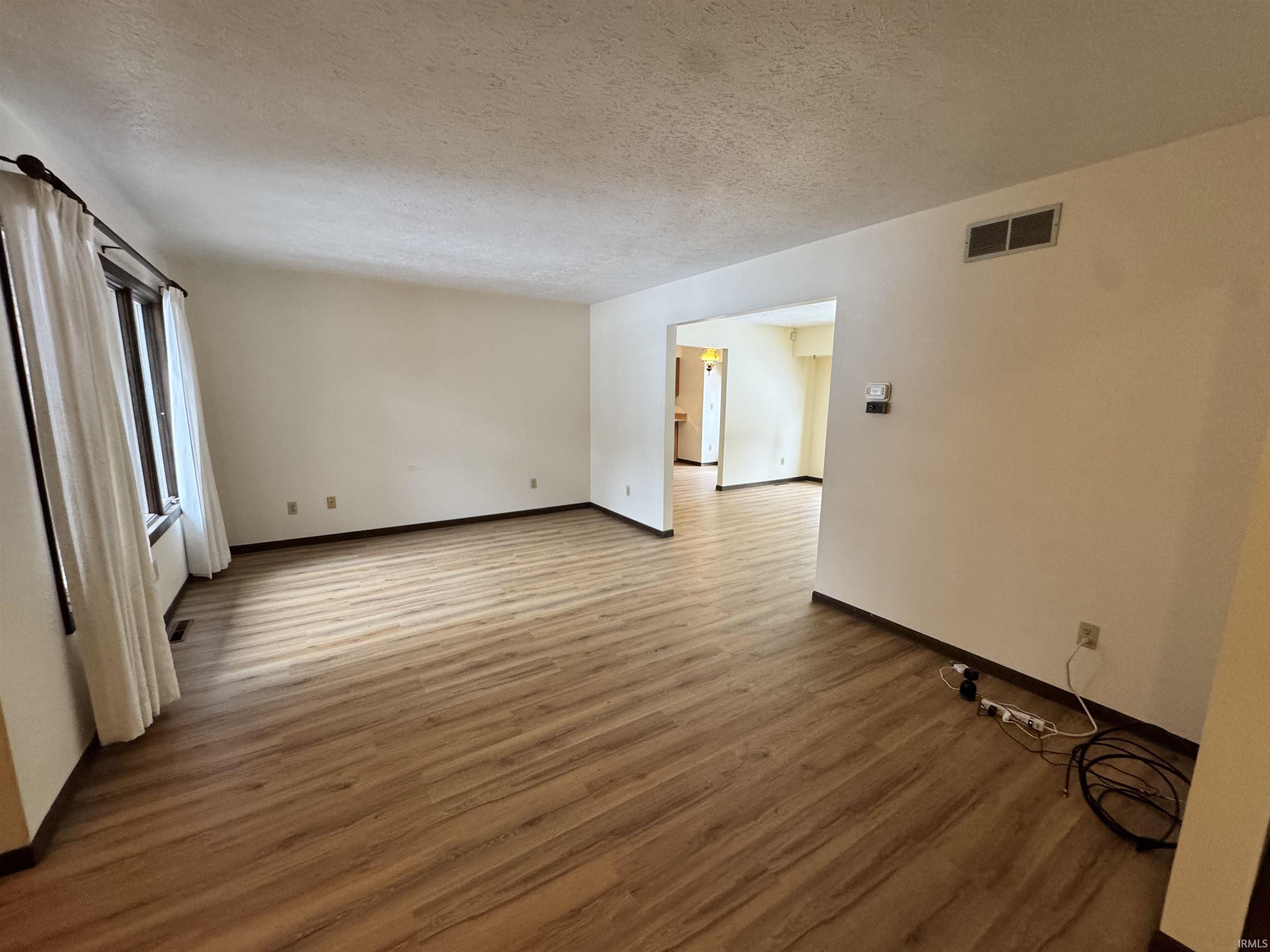 Empty room with a textured ceiling and wood finished floors