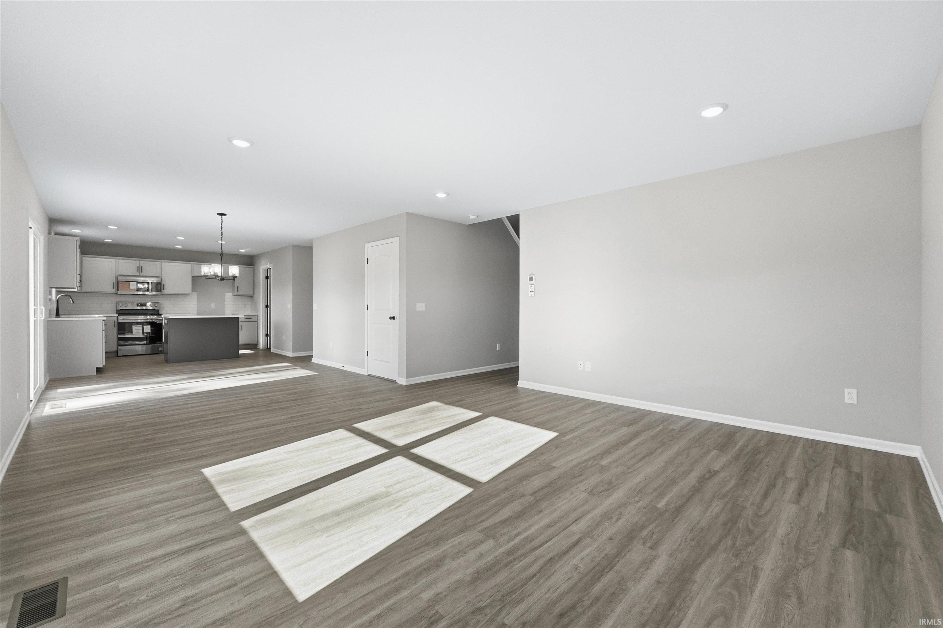 Unfurnished living room featuring recessed lighting, a chandelier, and dark wood-style floors