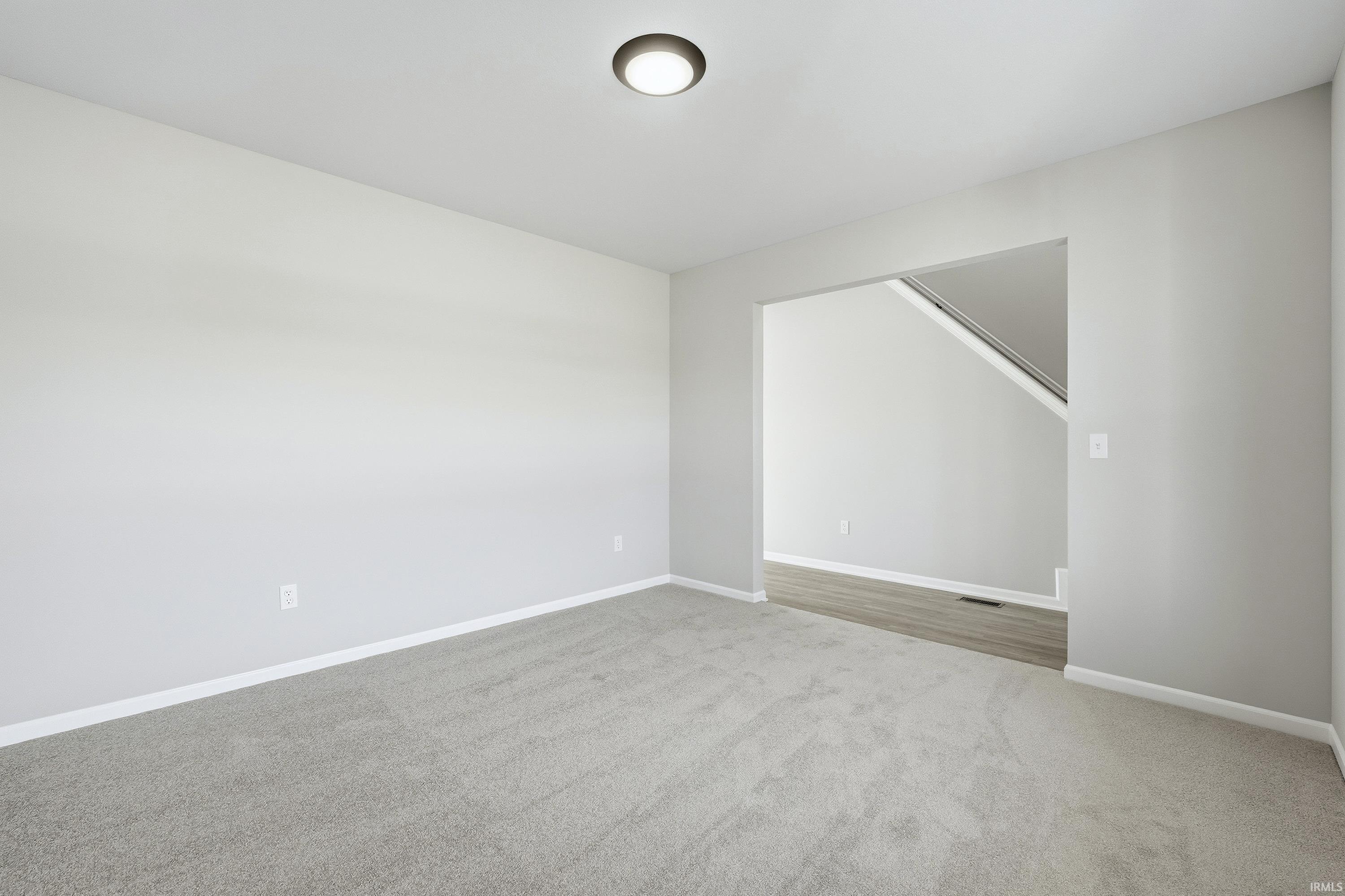 Empty room featuring light colored carpet and baseboards