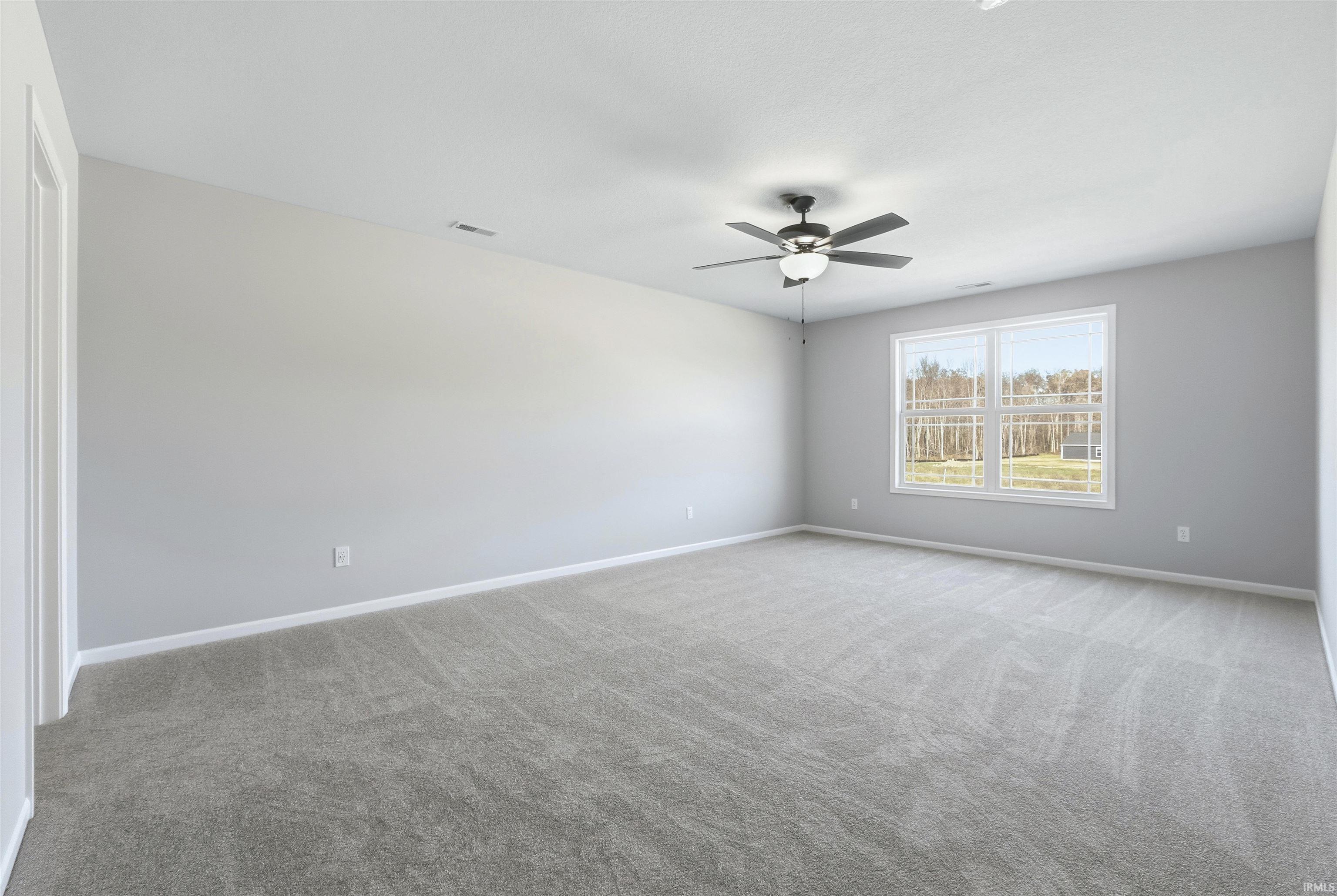 Carpeted empty room featuring baseboards and ceiling fan