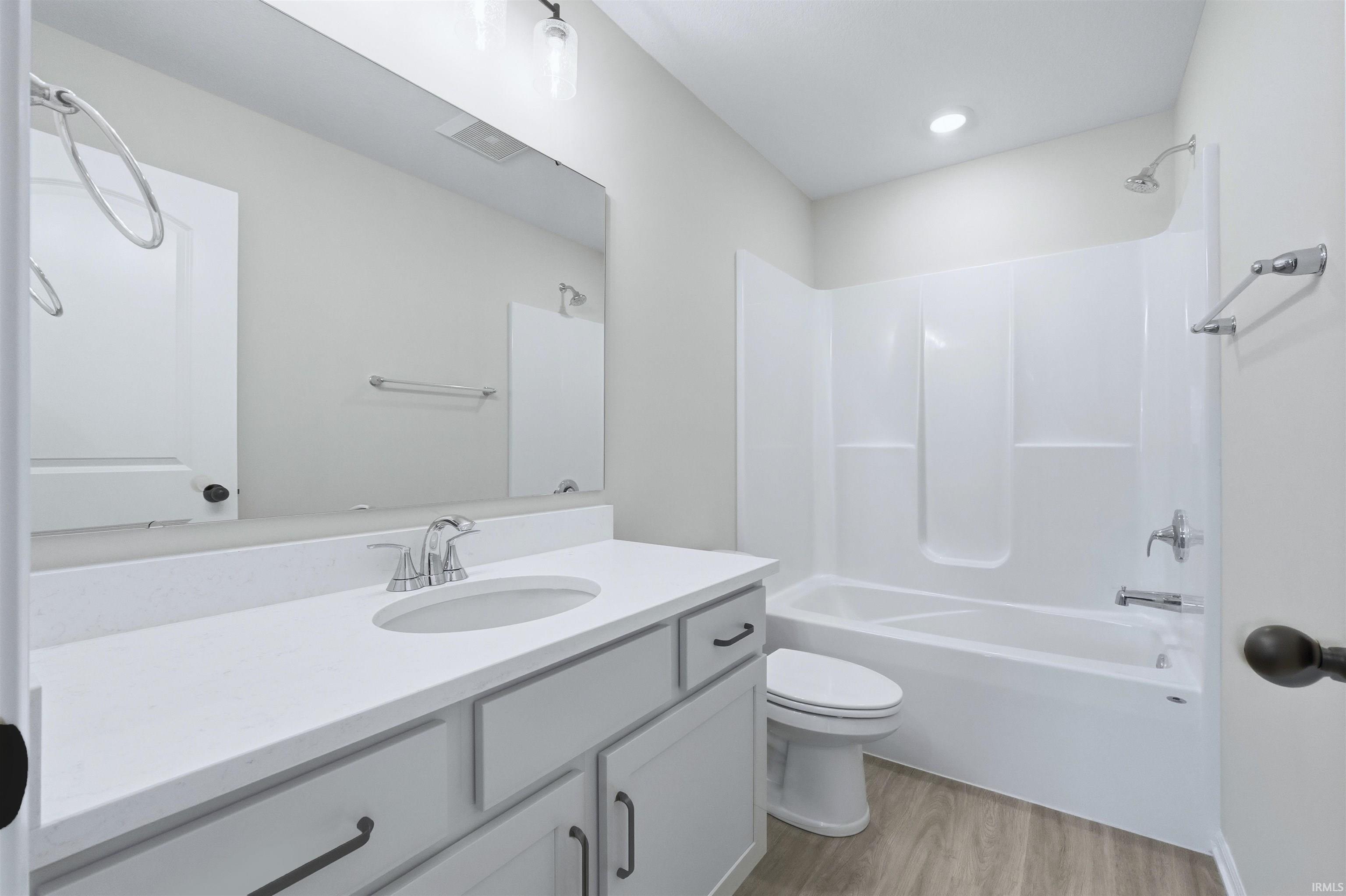 Bathroom featuring vanity, washtub / shower combination, and light wood-type flooring