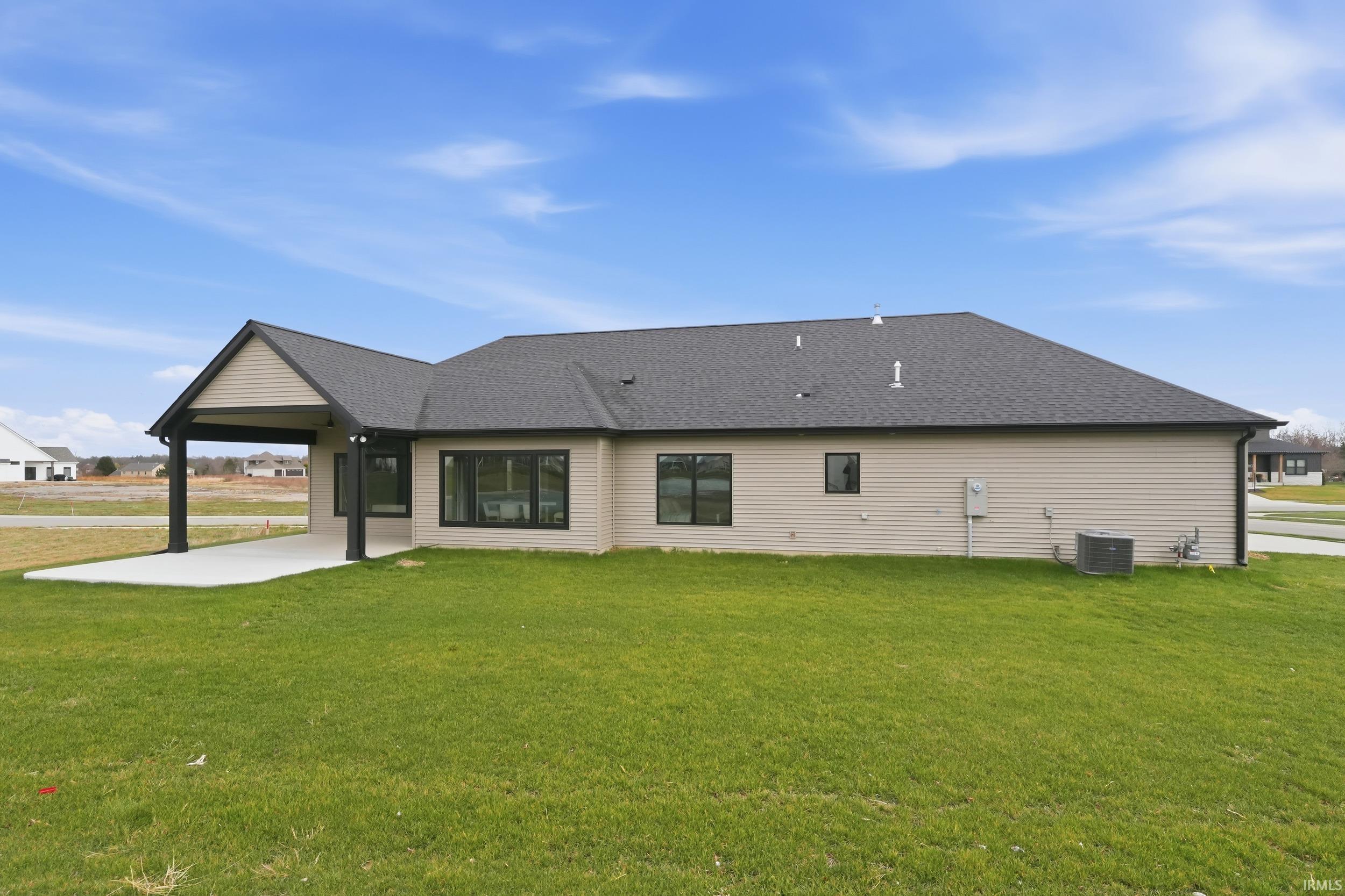 Rear view of property with a lawn, a patio area, and roof with shingles