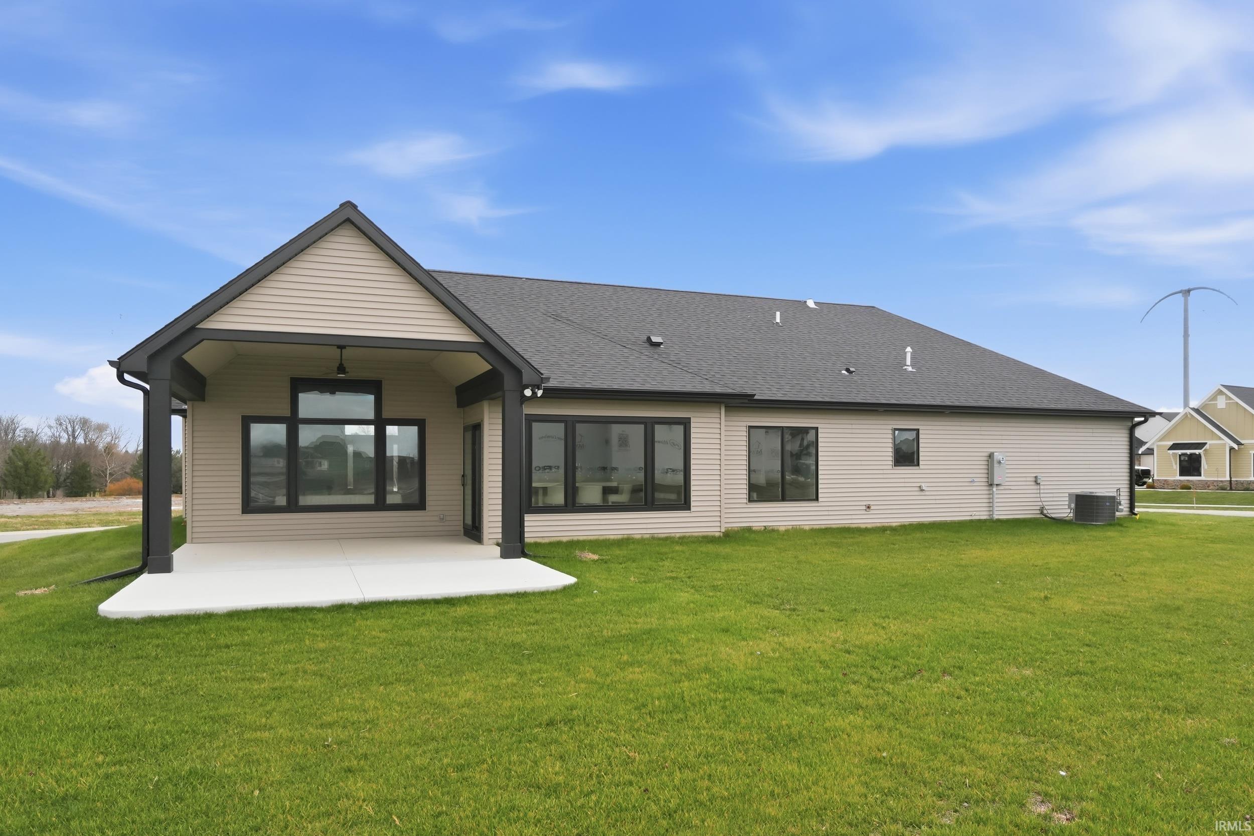 Rear view of property featuring a patio, a lawn, and roof with shingles