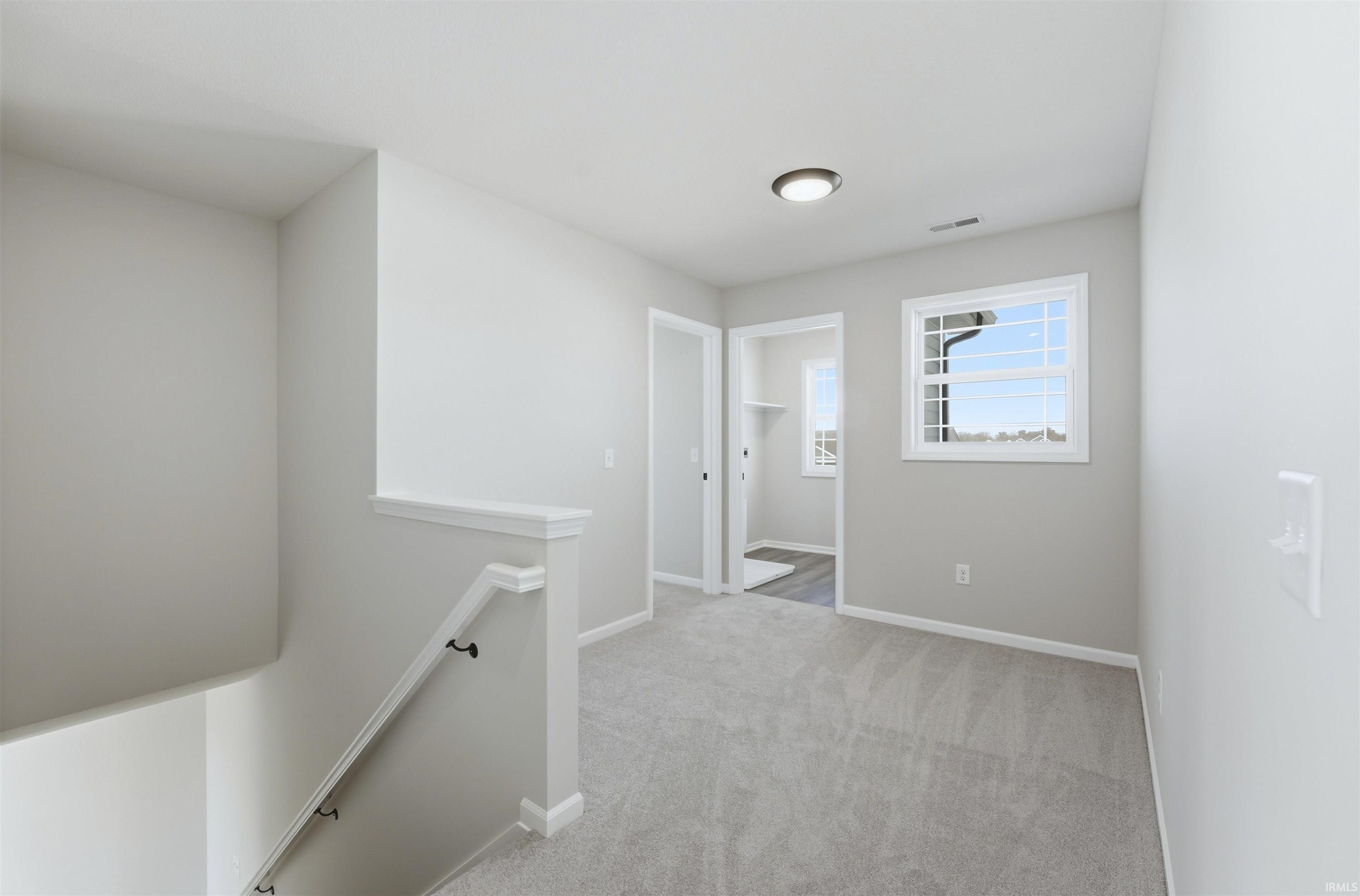 Corridor featuring an upstairs landing and light colored carpet
