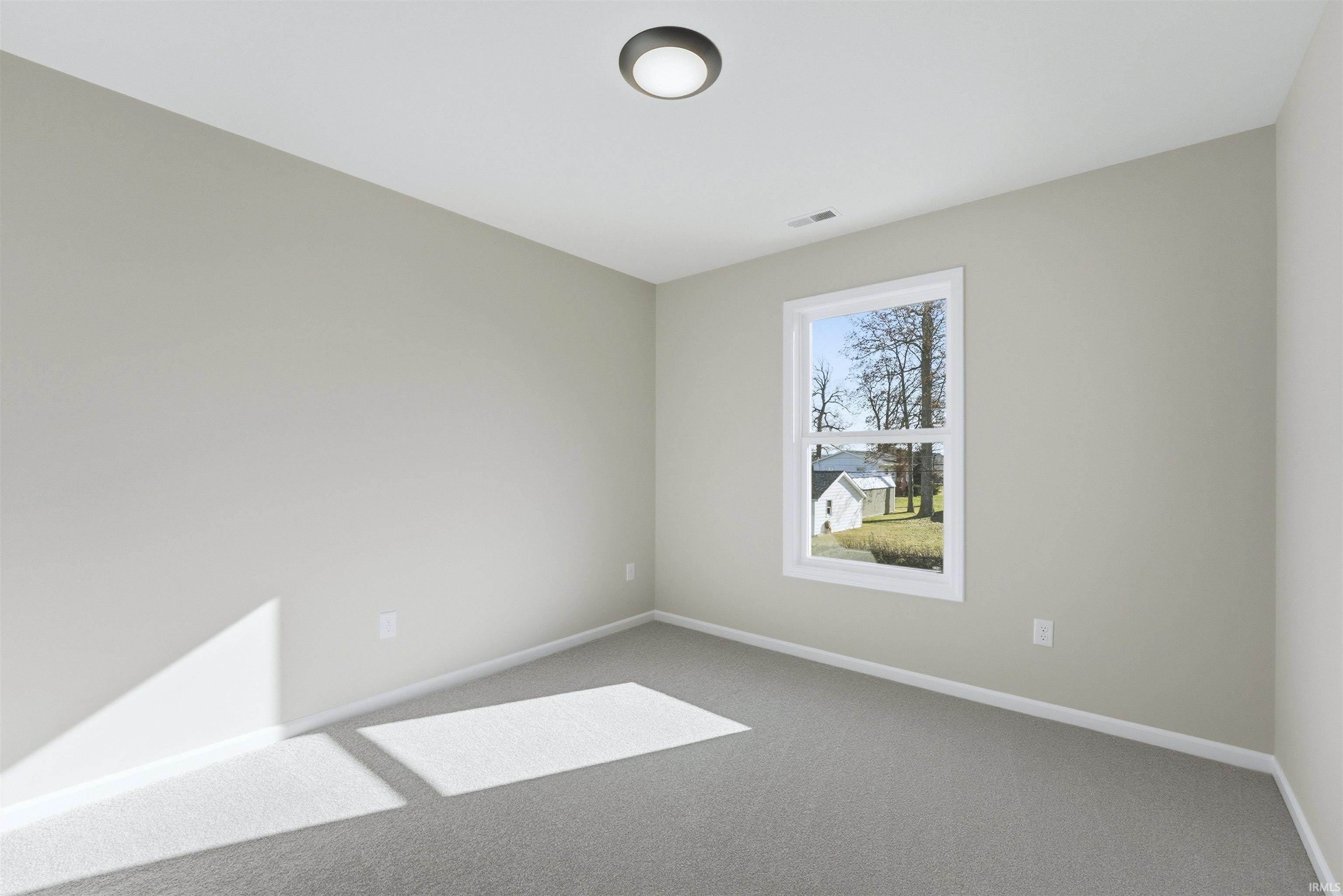 Carpeted spare room featuring baseboards