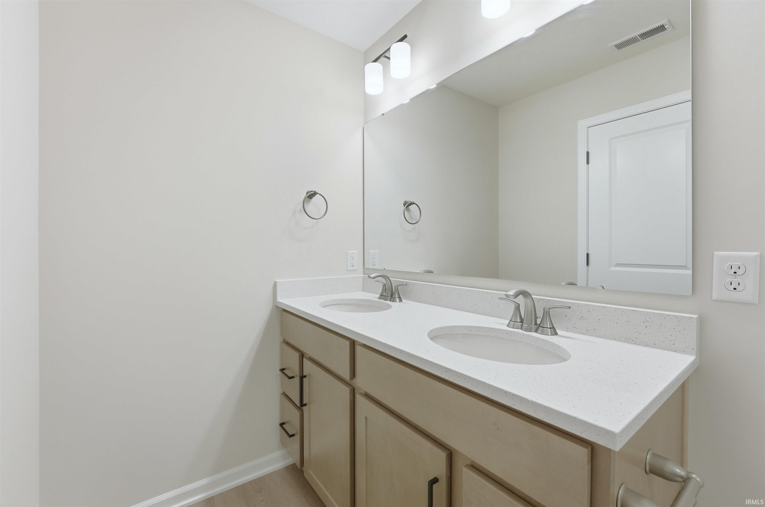 Full bath with double vanity and baseboards
