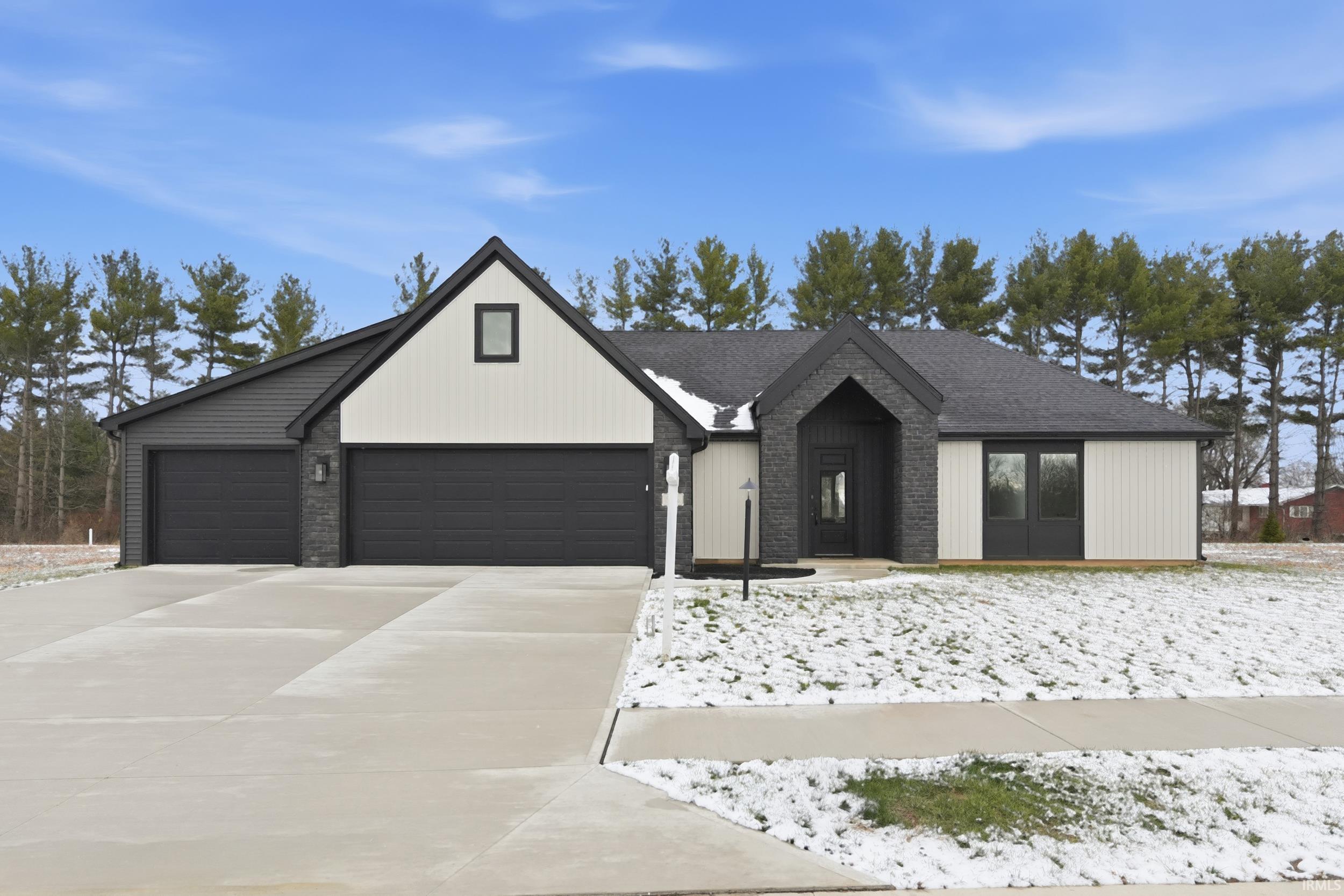 View of front facade with driveway, roof with shingles, and a garage