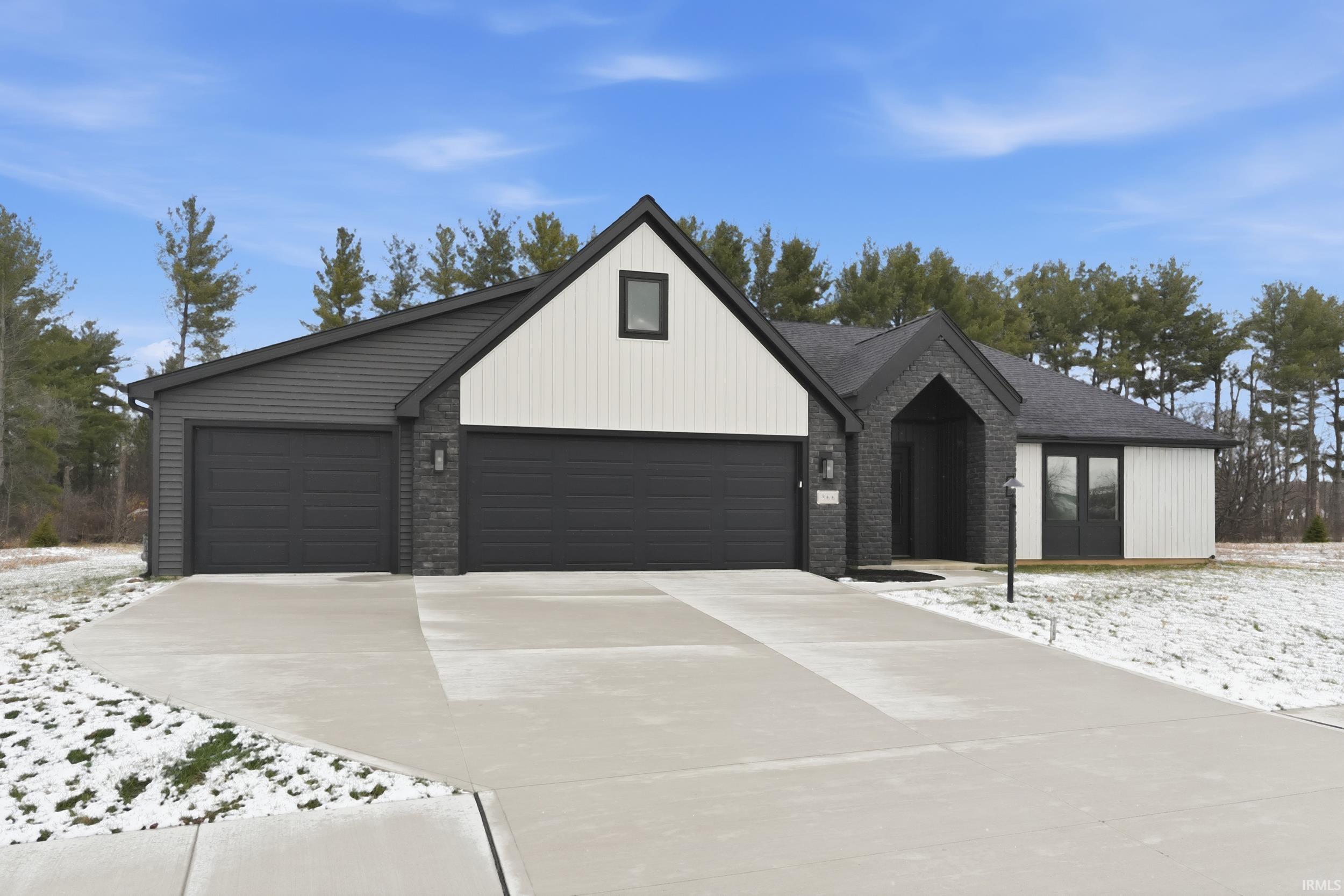 Modern inspired farmhouse featuring driveway, a garage, and brick siding