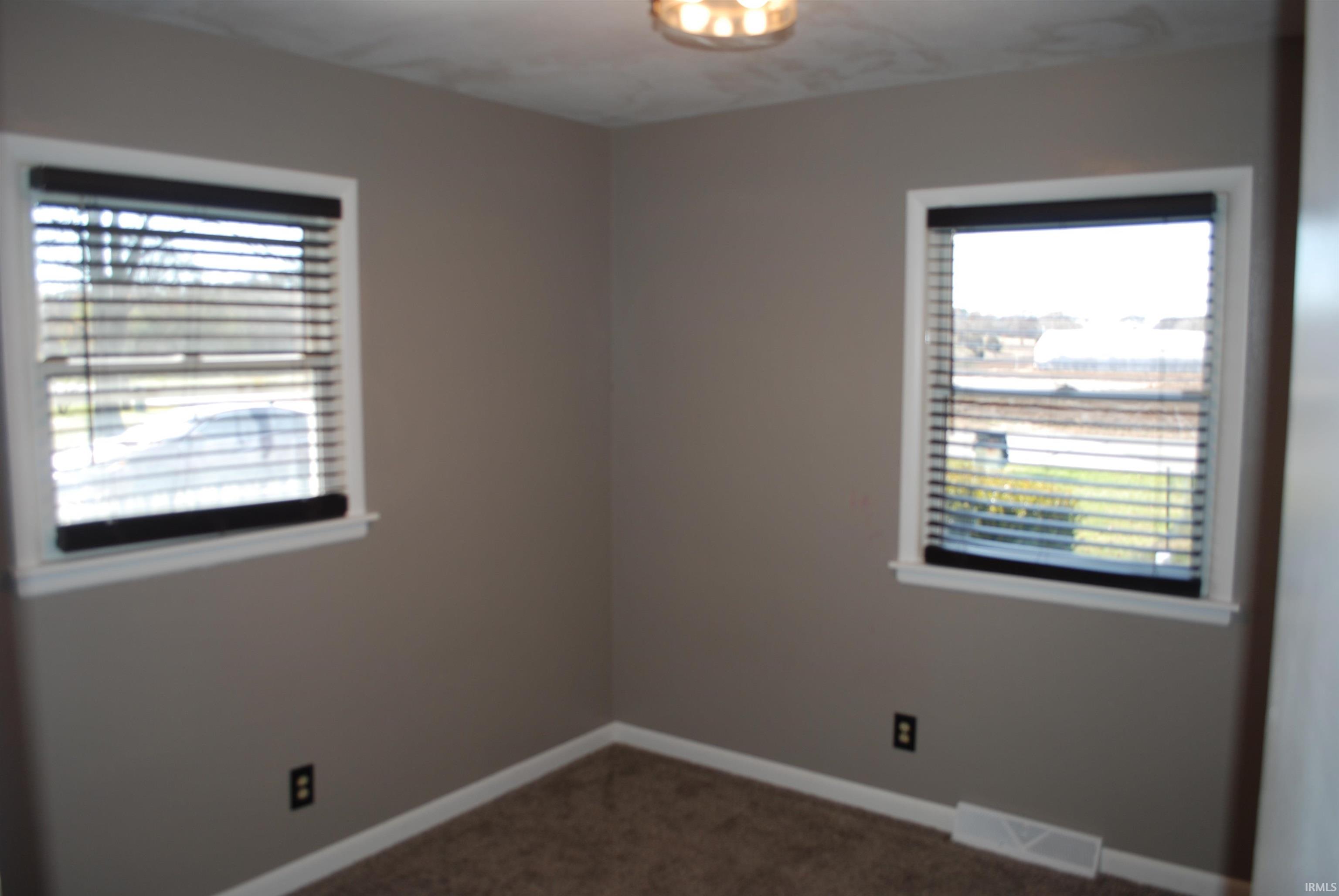 Spare room with dark colored carpet and baseboards