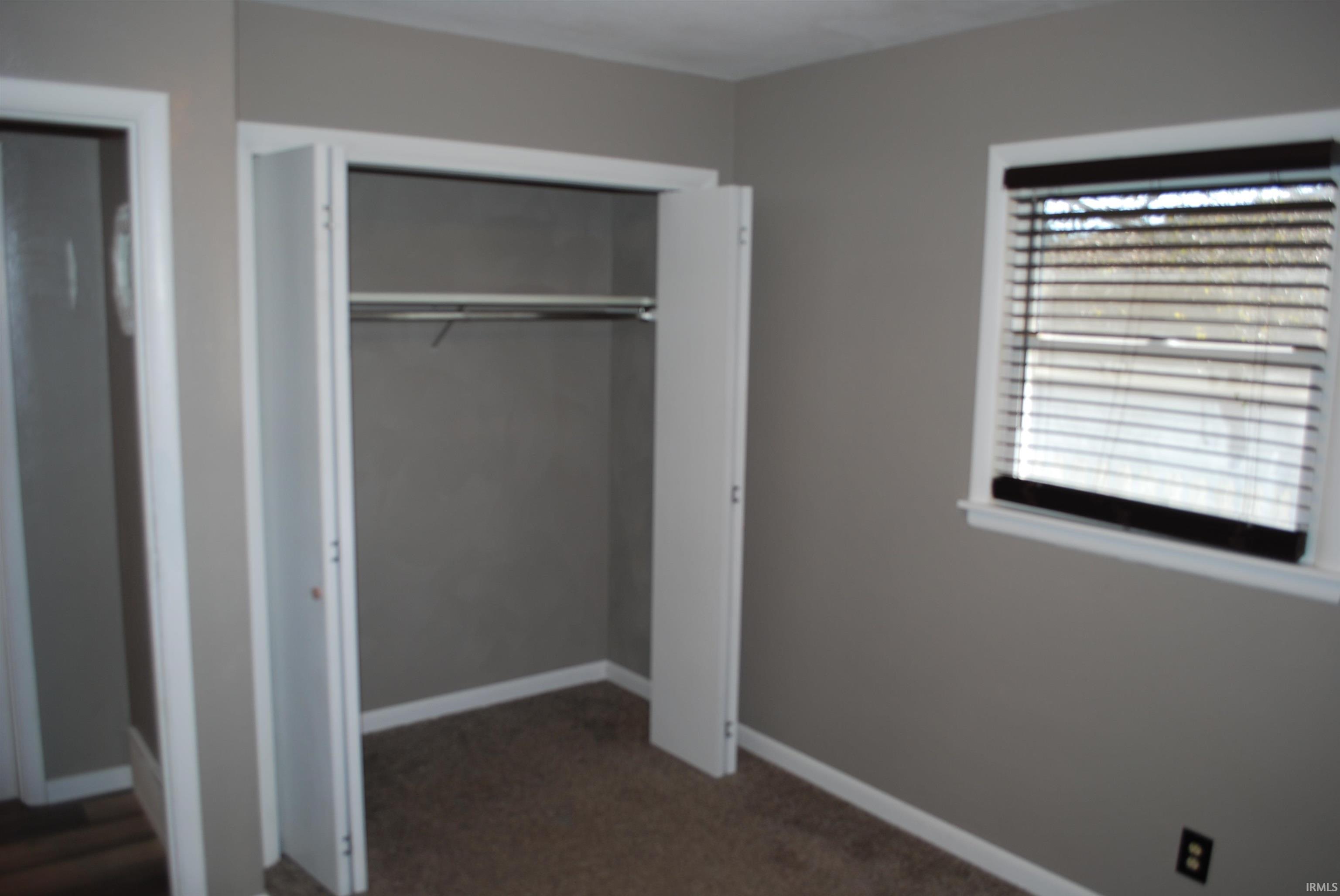 Unfurnished bedroom with a closet and dark carpet