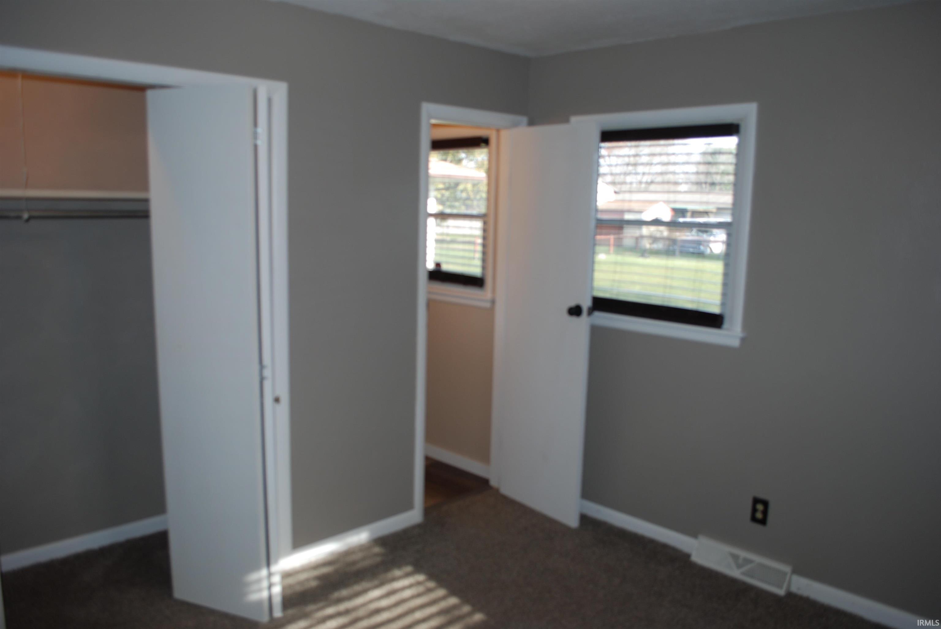 Unfurnished bedroom featuring dark carpet and a closet