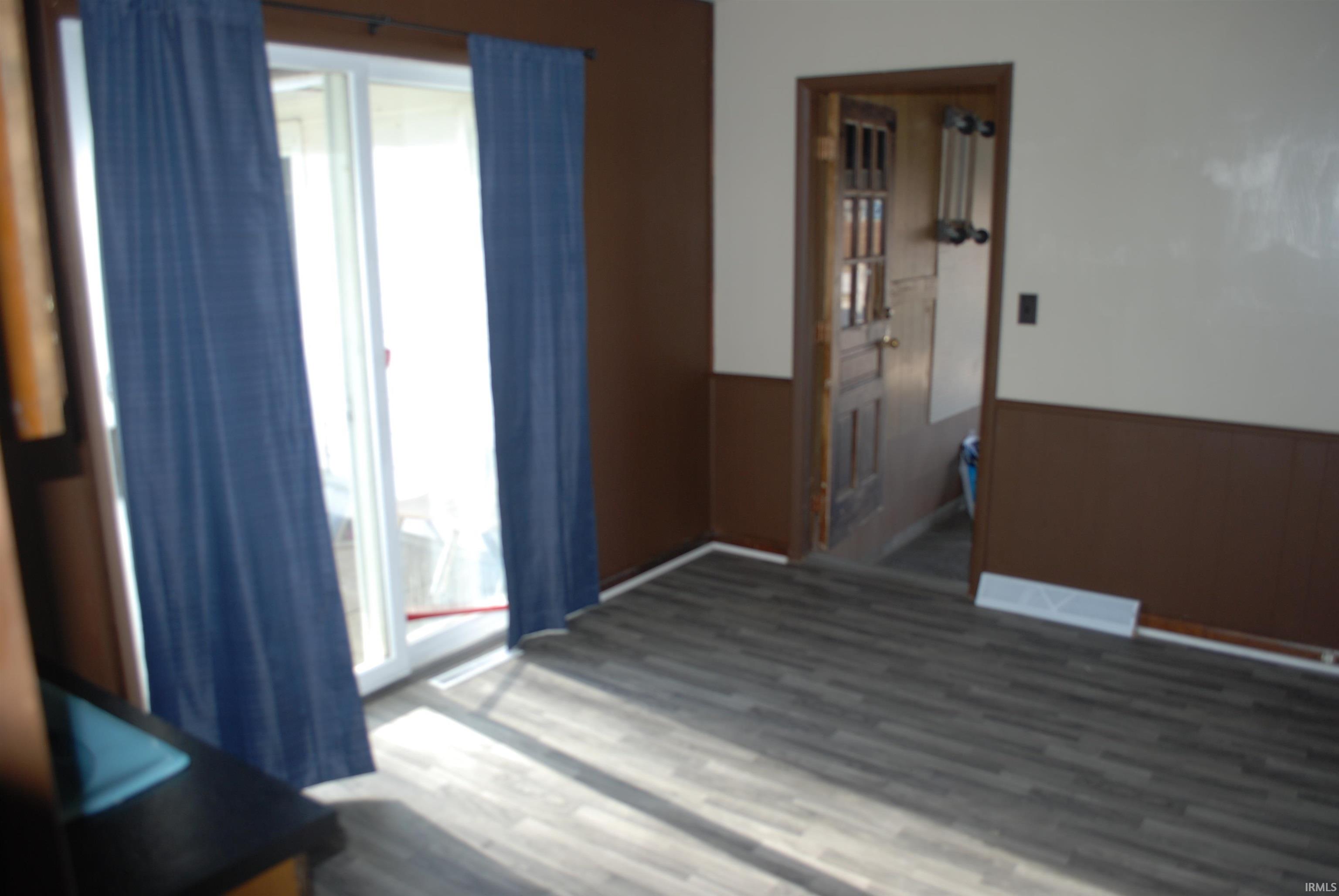 Spare room with a wainscoted wall, wood finished floors, and wooden walls