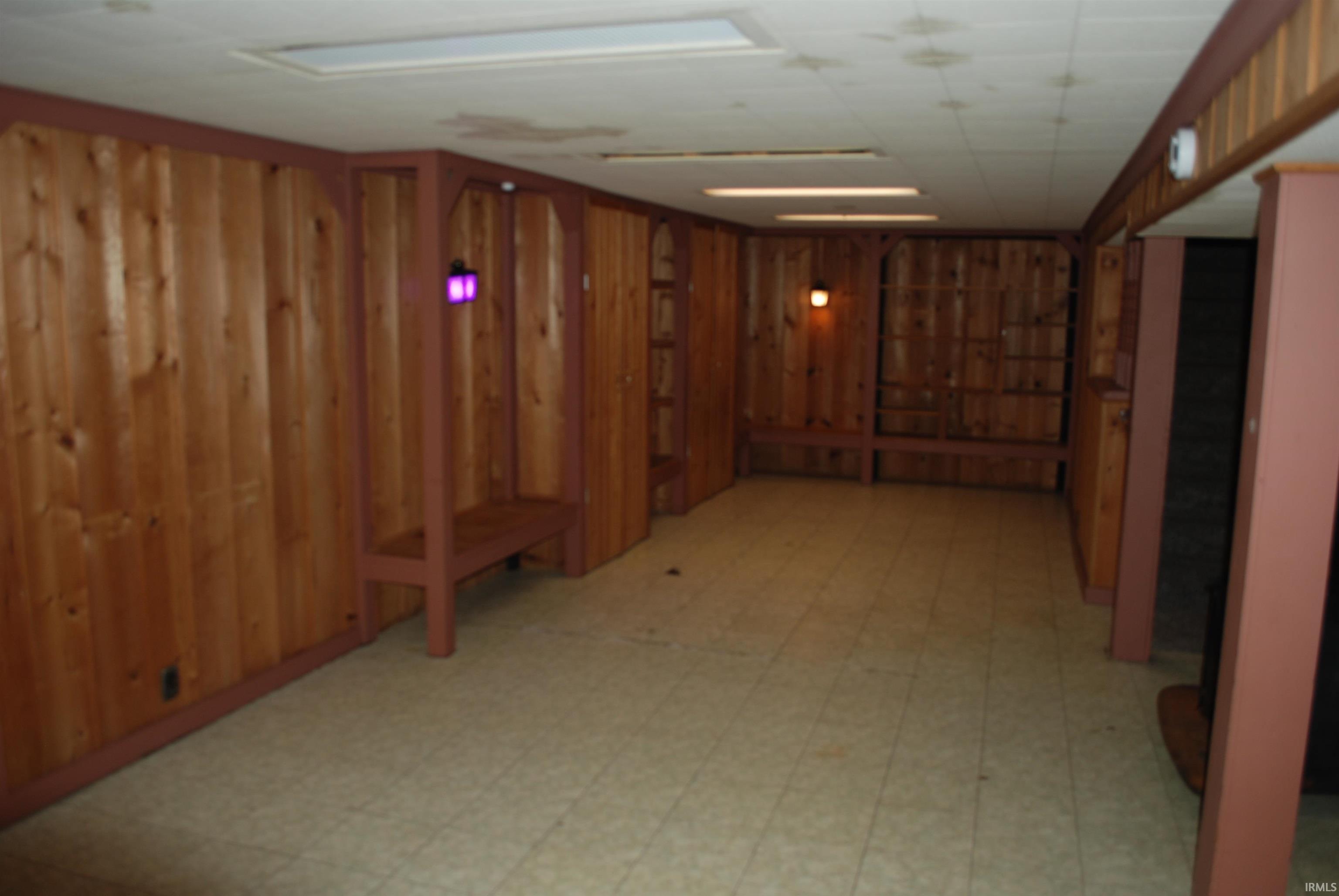 Below grade area featuring light flooring and wood walls