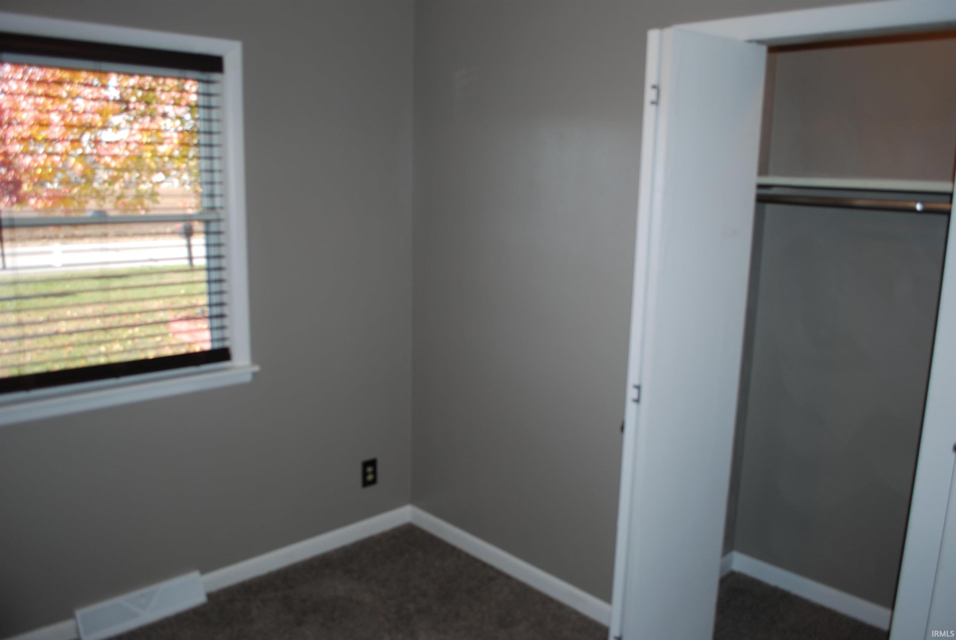 Unfurnished bedroom featuring a closet and dark colored carpet