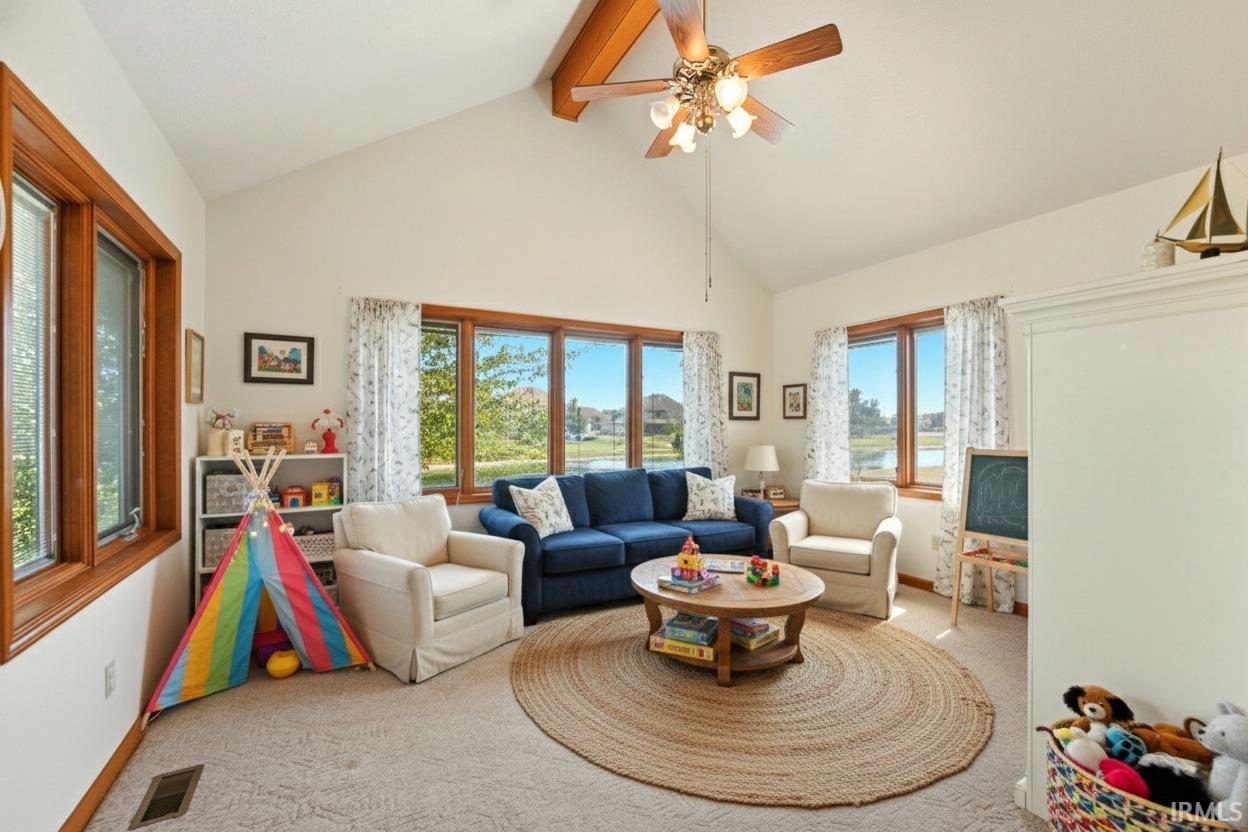 Living room featuring high vaulted ceiling, beam ceiling, carpet flooring, and ceiling fan