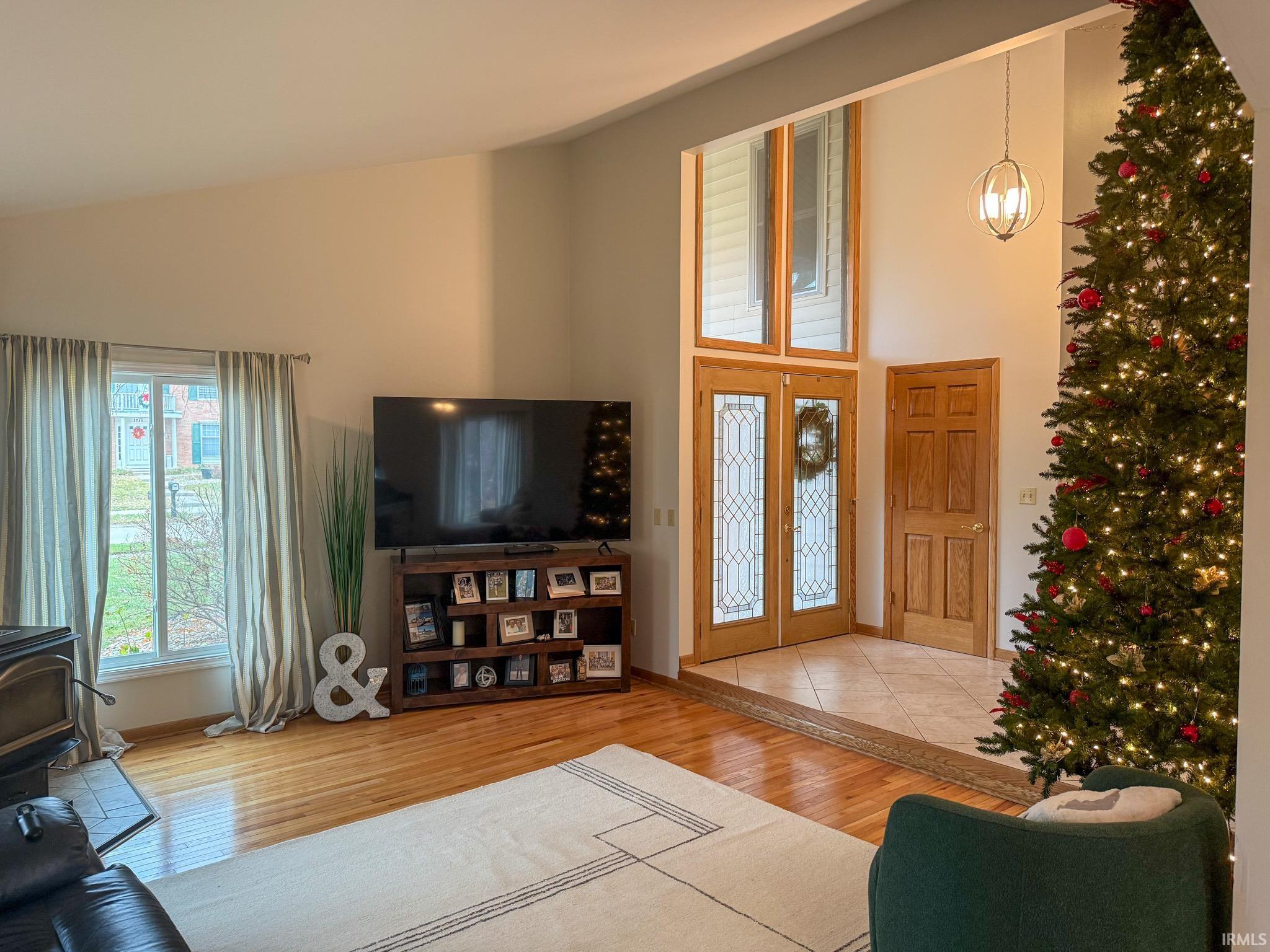 Living room featuring wood finished floors, high vaulted ceiling, and a wood stove