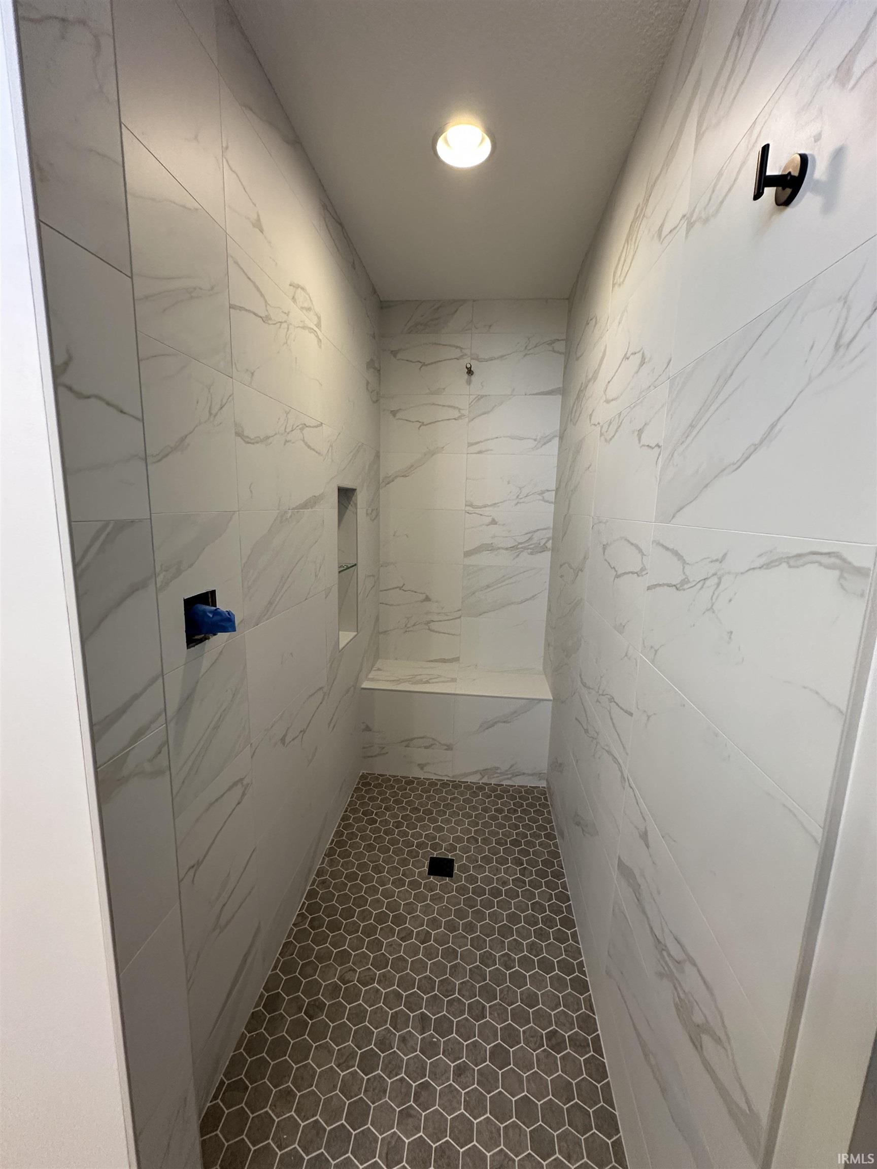 Bathroom with a marble finish shower and recessed lighting