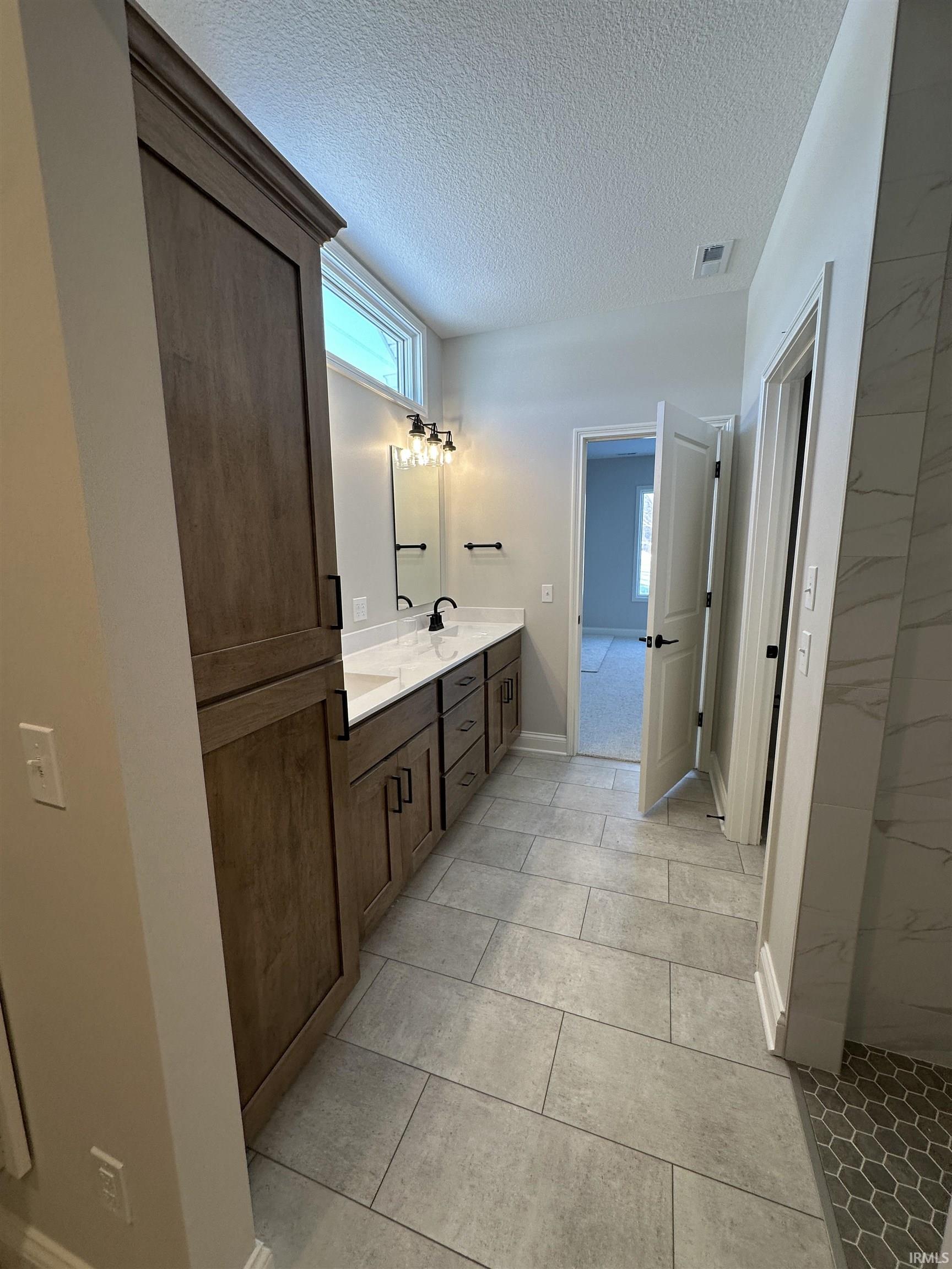 Full bath with double vanity and a textured ceiling