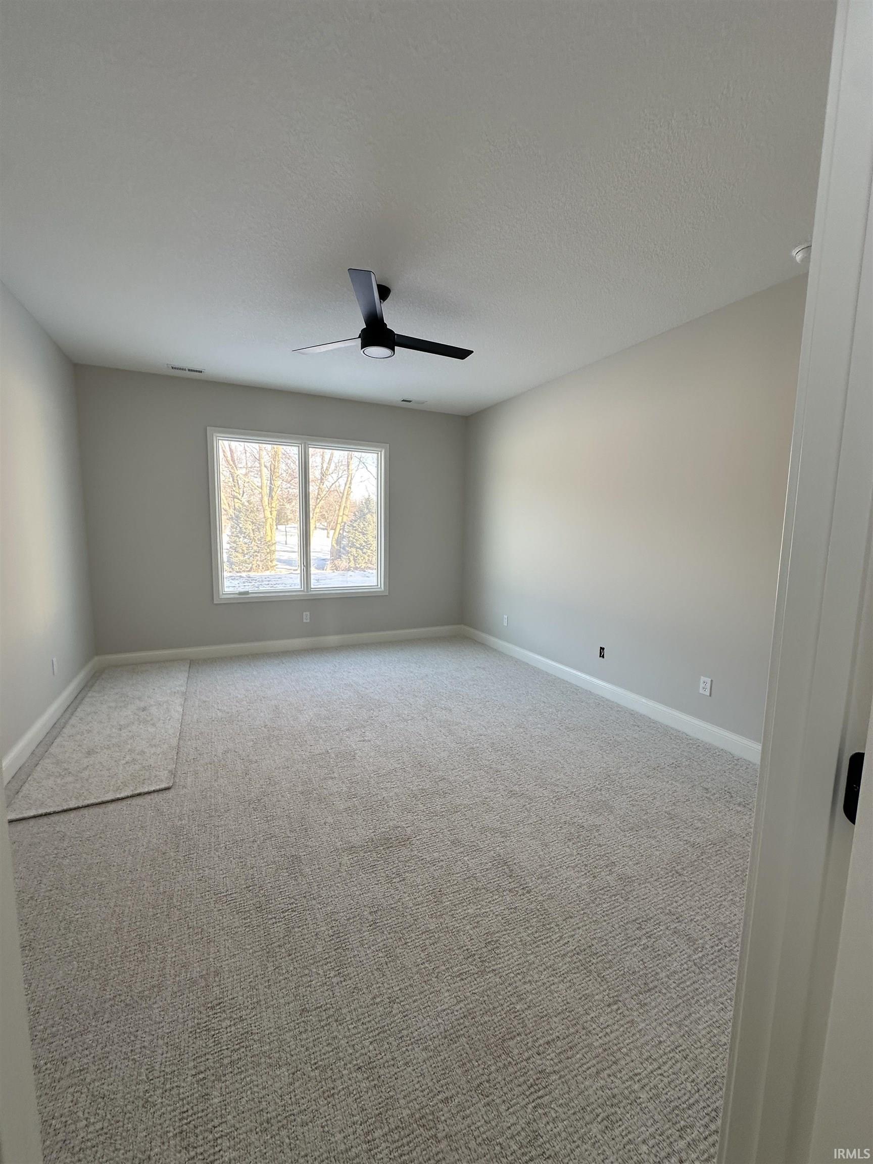 Spare room with carpet flooring, a textured ceiling, and a ceiling fan