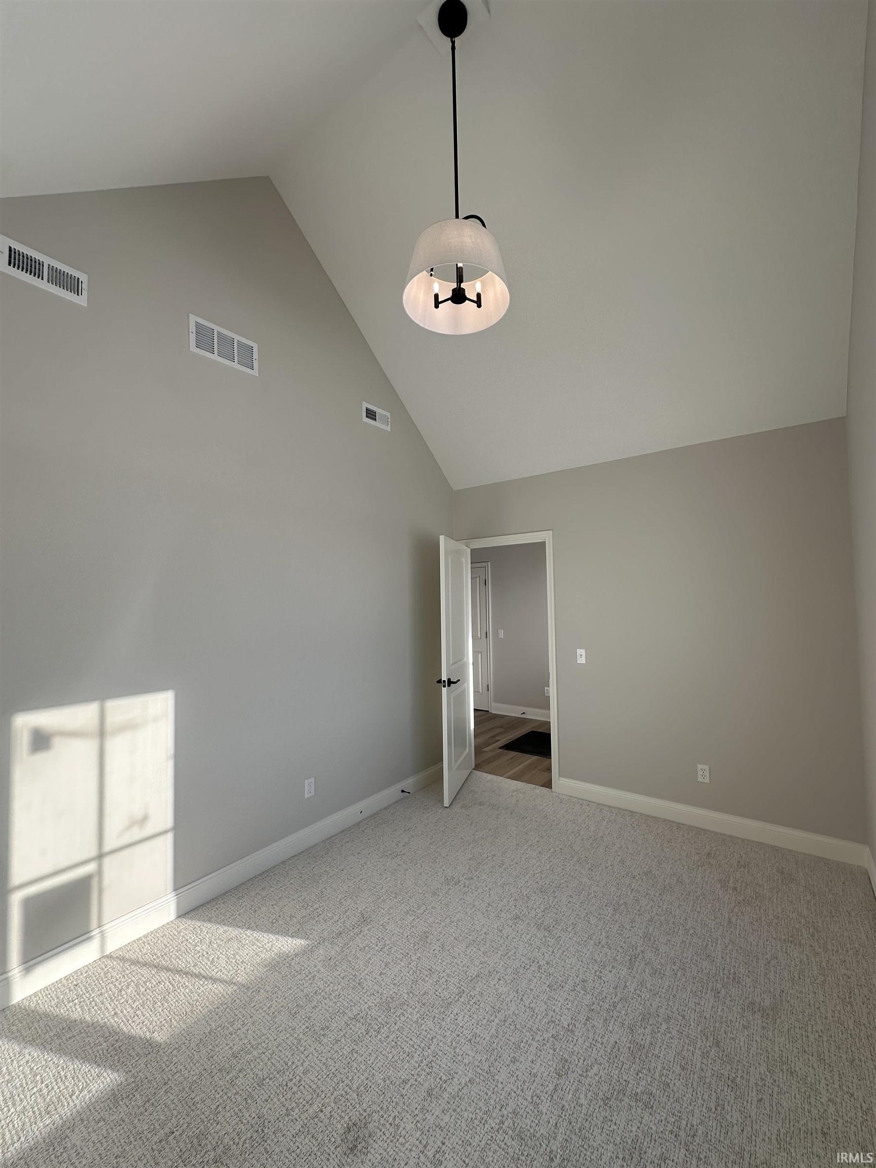 Unfurnished room with high vaulted ceiling and carpet