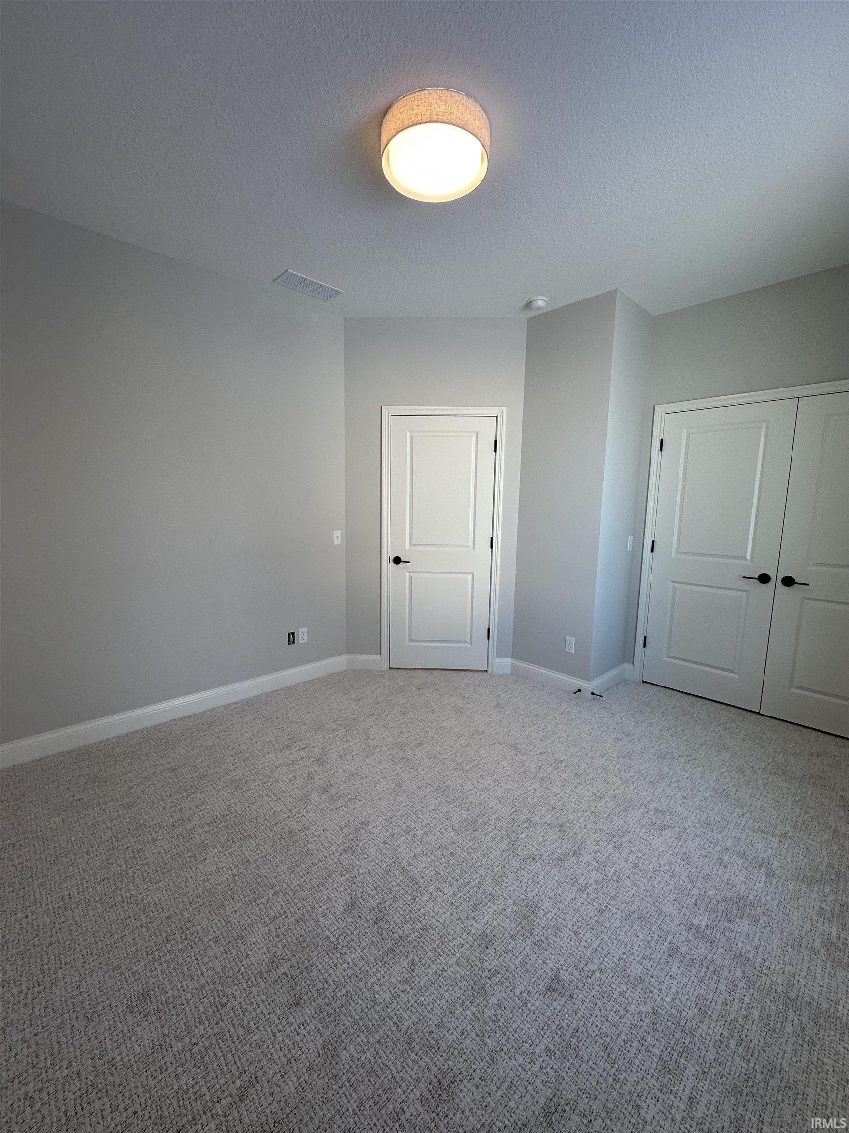 Unfurnished bedroom with a textured ceiling, carpet floors, and a closet